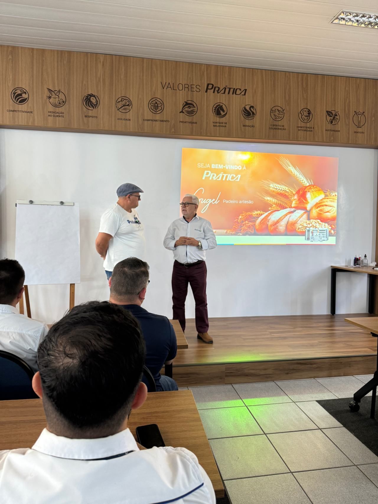 Um homem está fazendo uma apresentação para um grupo de pessoas em uma sala de aula.