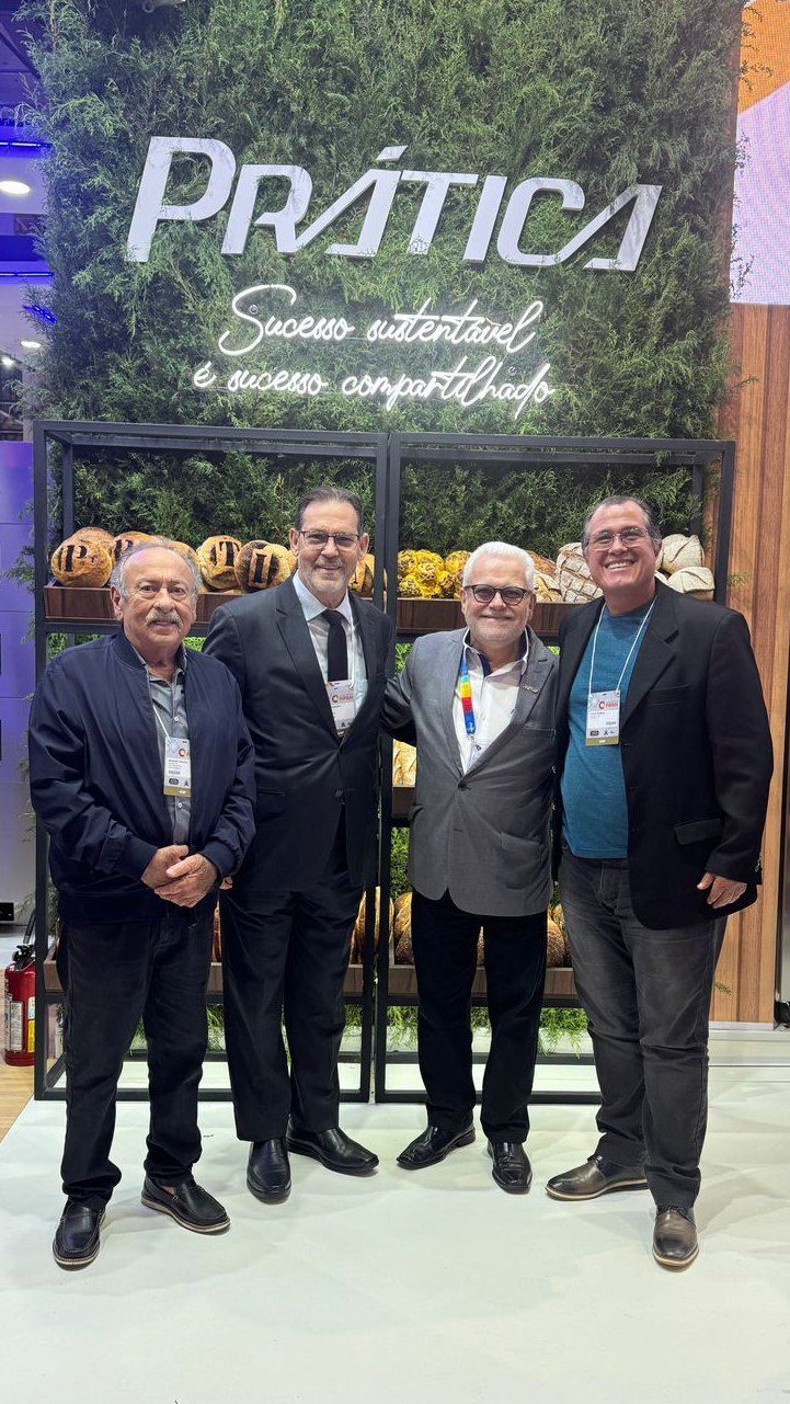 Um grupo de homens está posando para uma foto em frente a uma placa.