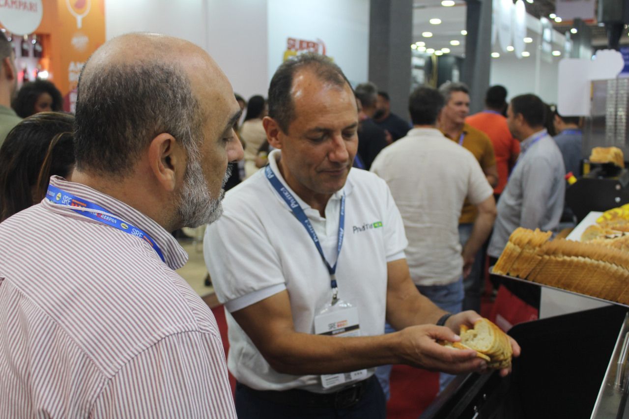 Um homem está segurando um pedaço de pão e conversando com outro homem