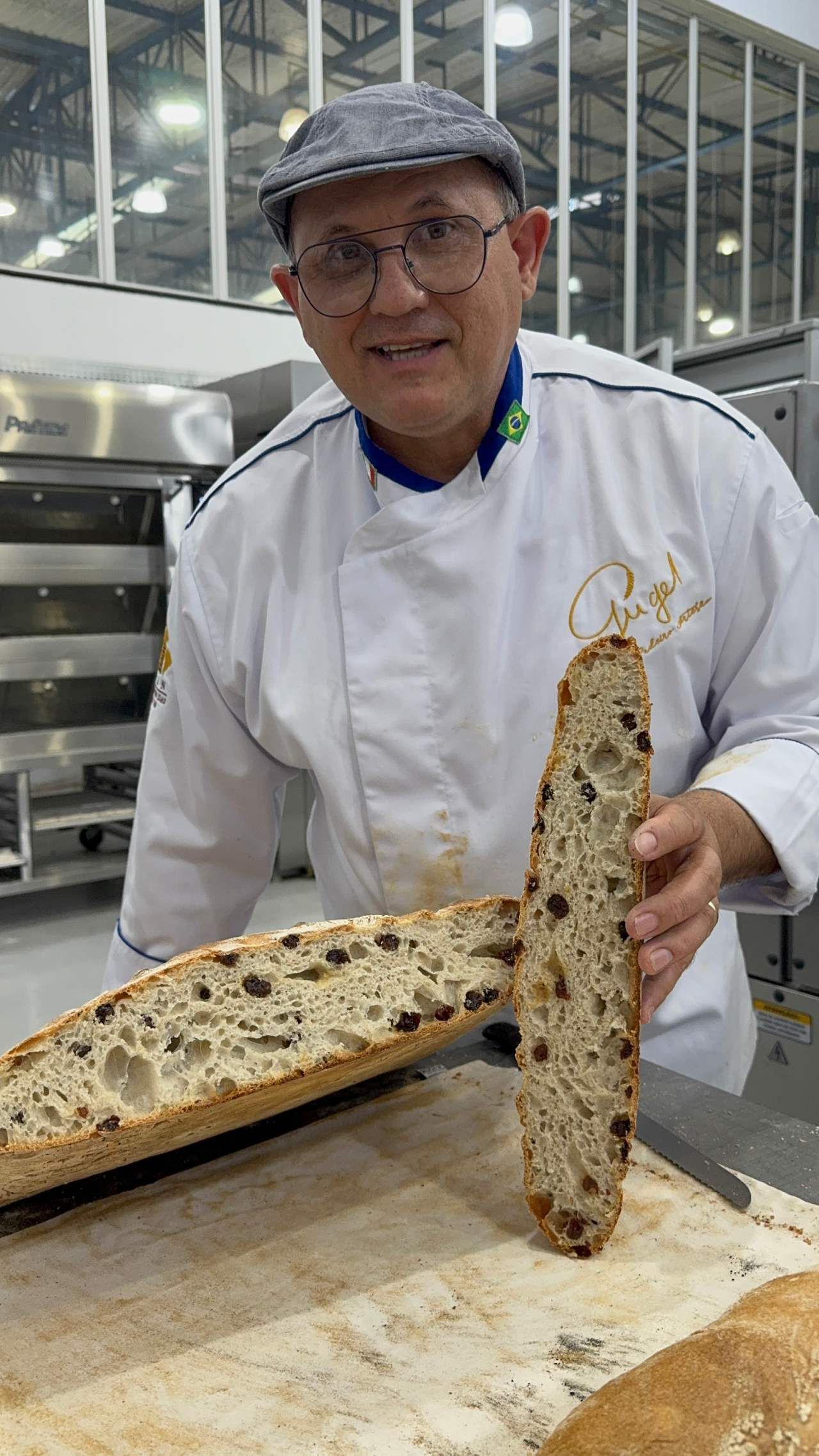 Um homem com uniforme de chef está segurando um pedaço de pão.