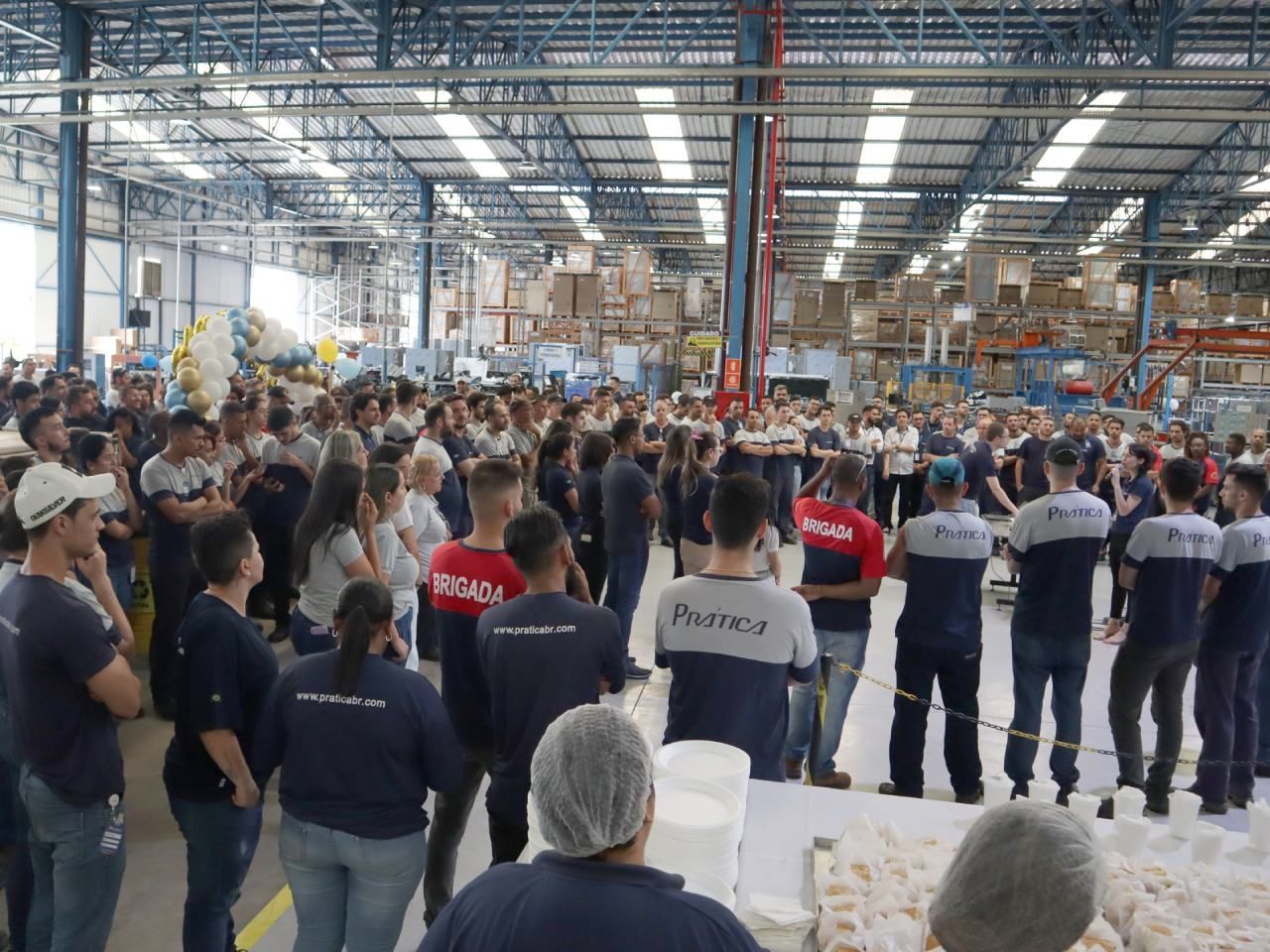 Um grande grupo de pessoas está em um armazém.