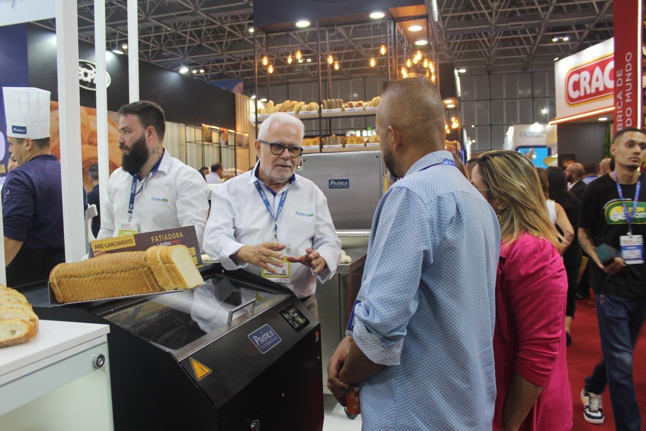 Um grupo de pessoas está ao redor de uma máquina em uma padaria.