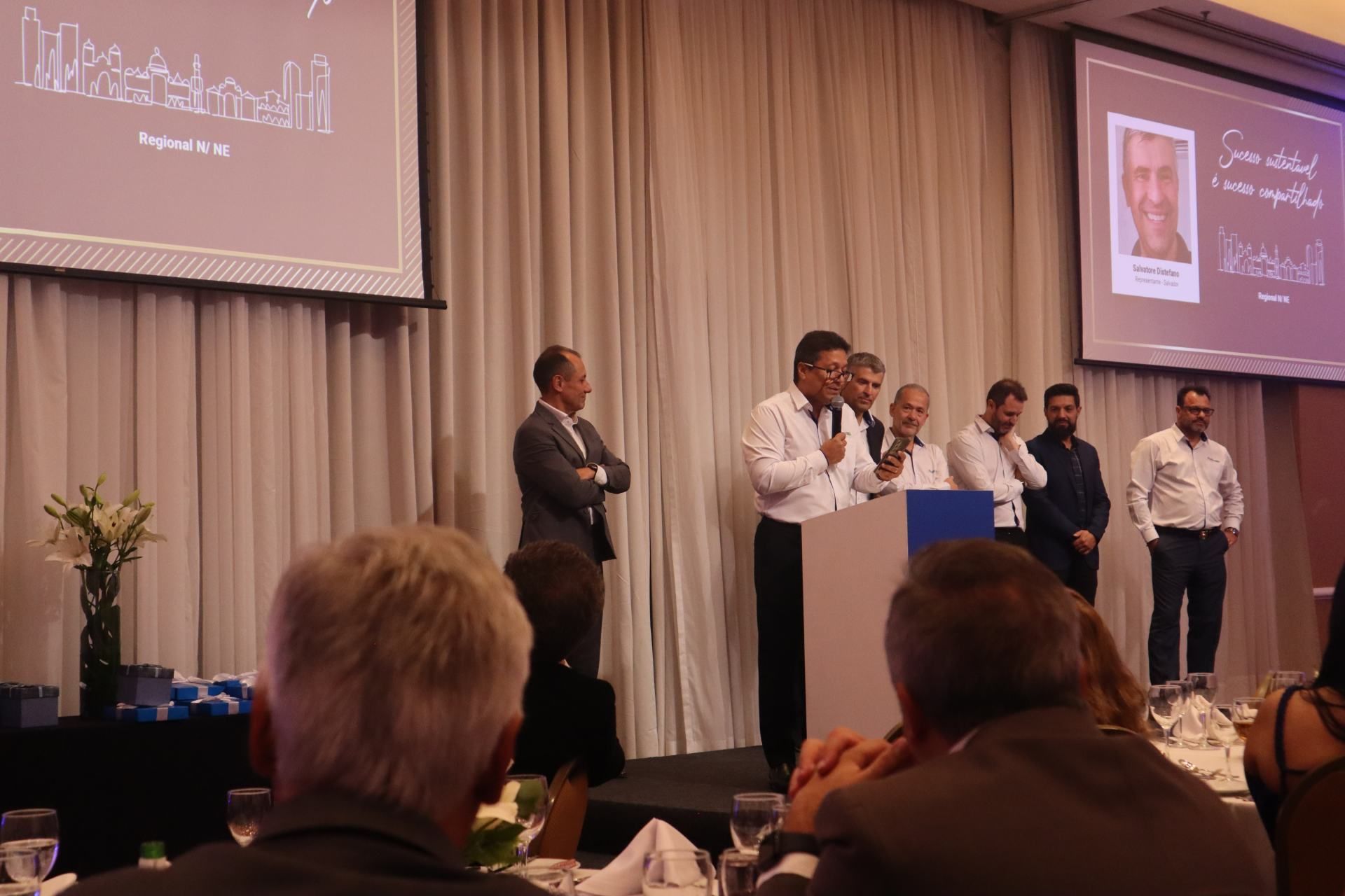 Um grupo de homens está em um palco fazendo uma apresentação.
