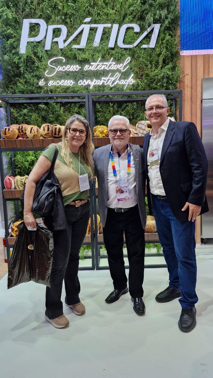 Um grupo de pessoas está posando para uma foto em frente a uma placa.