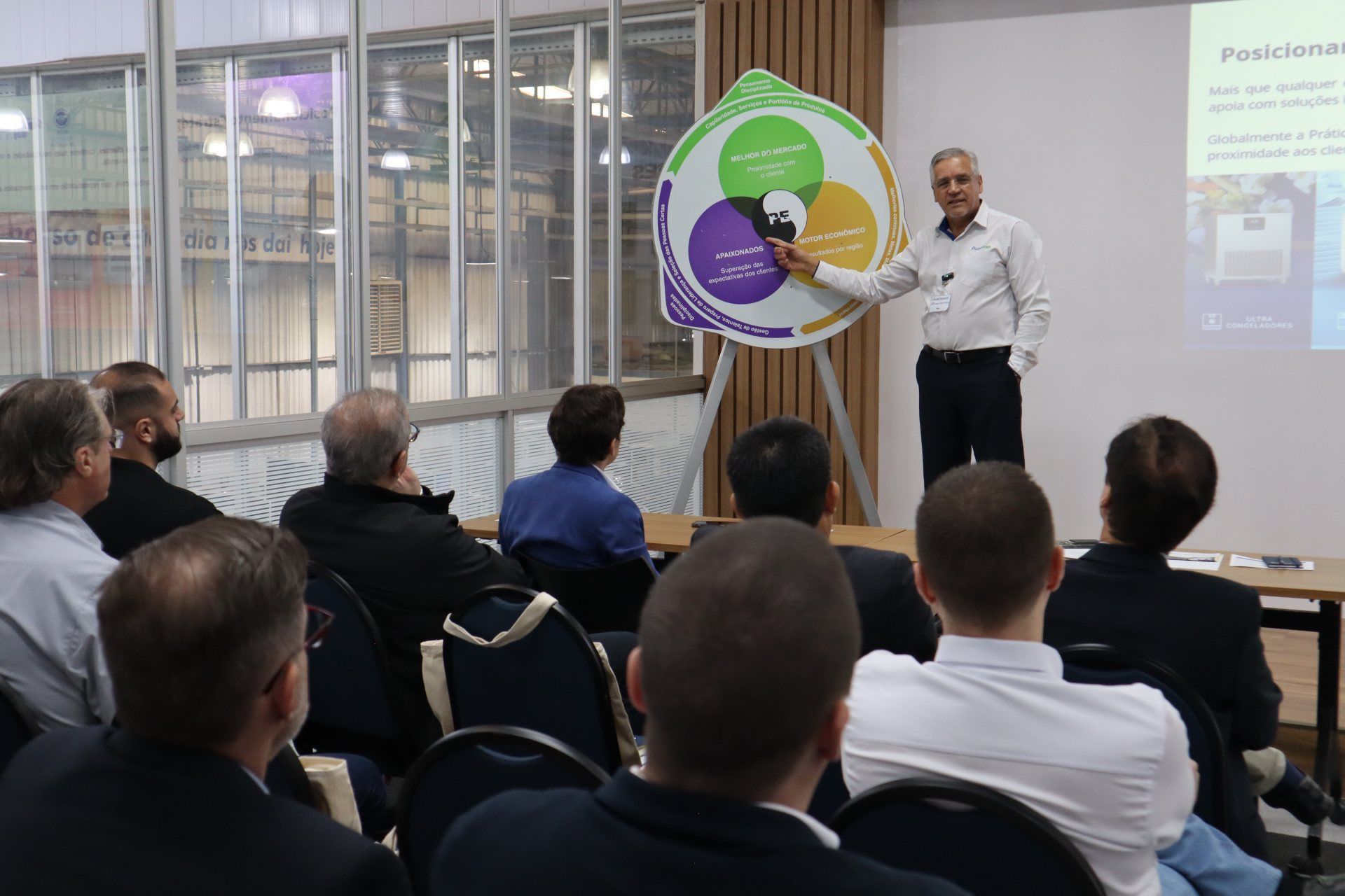 Um homem está fazendo uma apresentação para um grupo de pessoas sentadas em cadeiras.