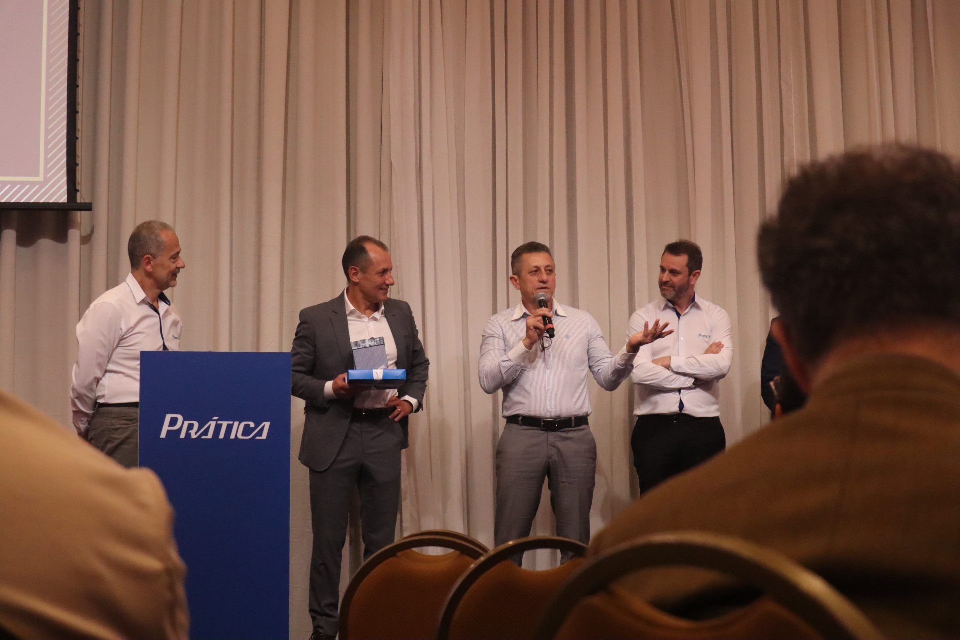 Um grupo de homens está em pé em frente a um pódio que diz primos