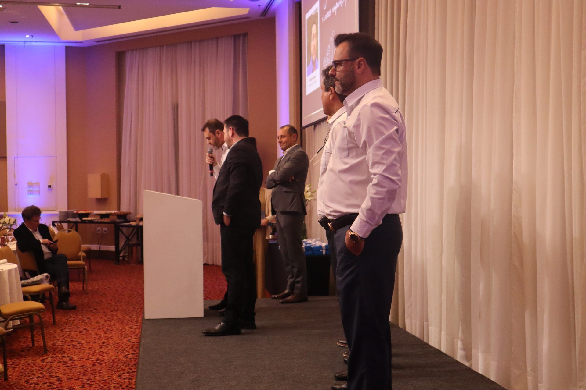 Um grupo de homens está em pé em frente a um pódio em uma sala de conferências.