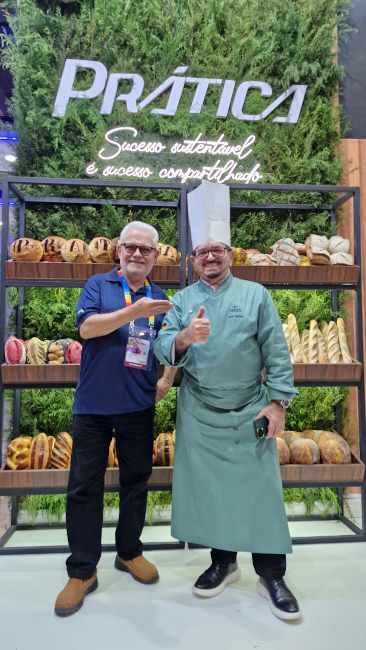 Dois homens estão parados um ao lado do outro em frente a uma exposição de comida.