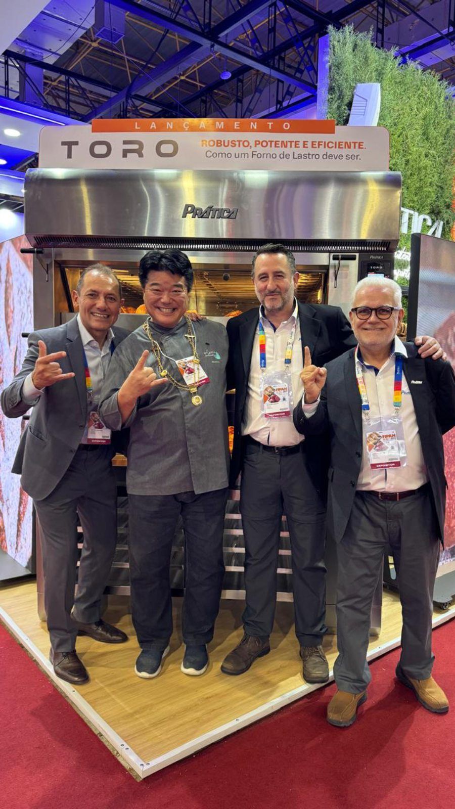 Um grupo de homens está posando para uma foto em frente a um forno toro.
