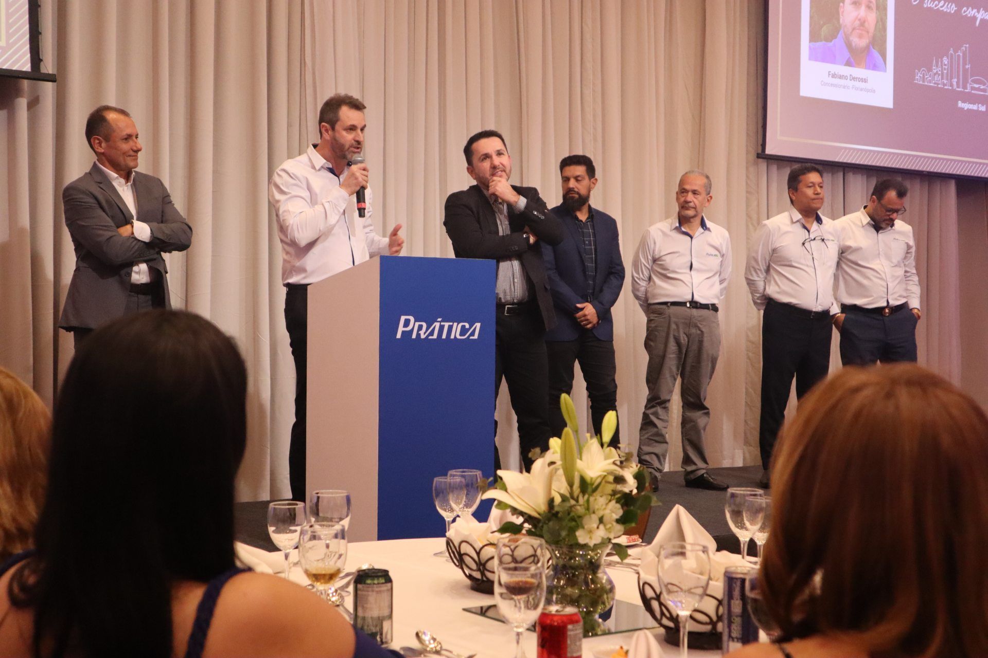 Um grupo de homens está em pé na frente de um pódio com a palavra primos escrita nele.