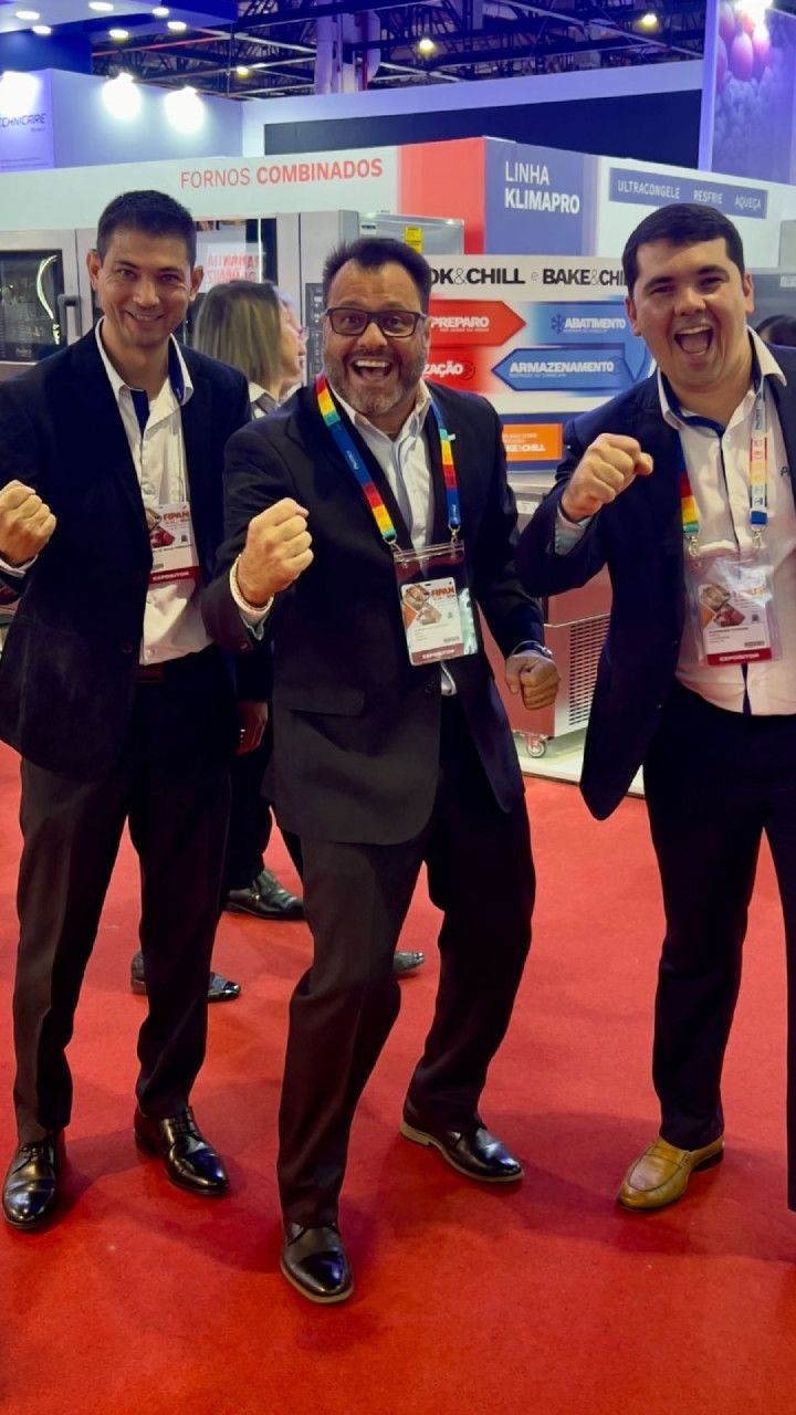 Três homens de terno estão posando para uma foto no tapete vermelho.