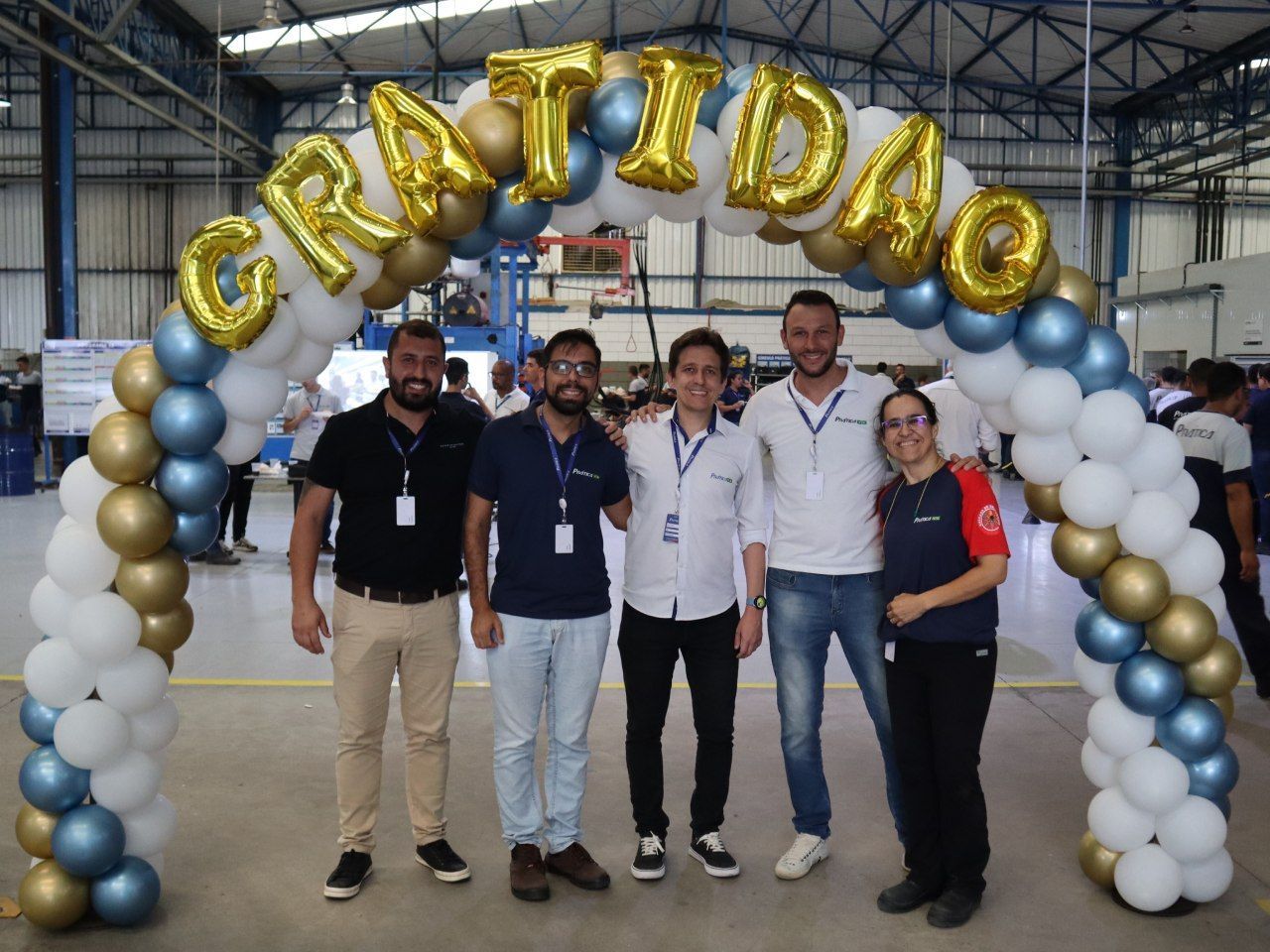 Um grupo de pessoas em pé sob um arco de balões que diz gratidao