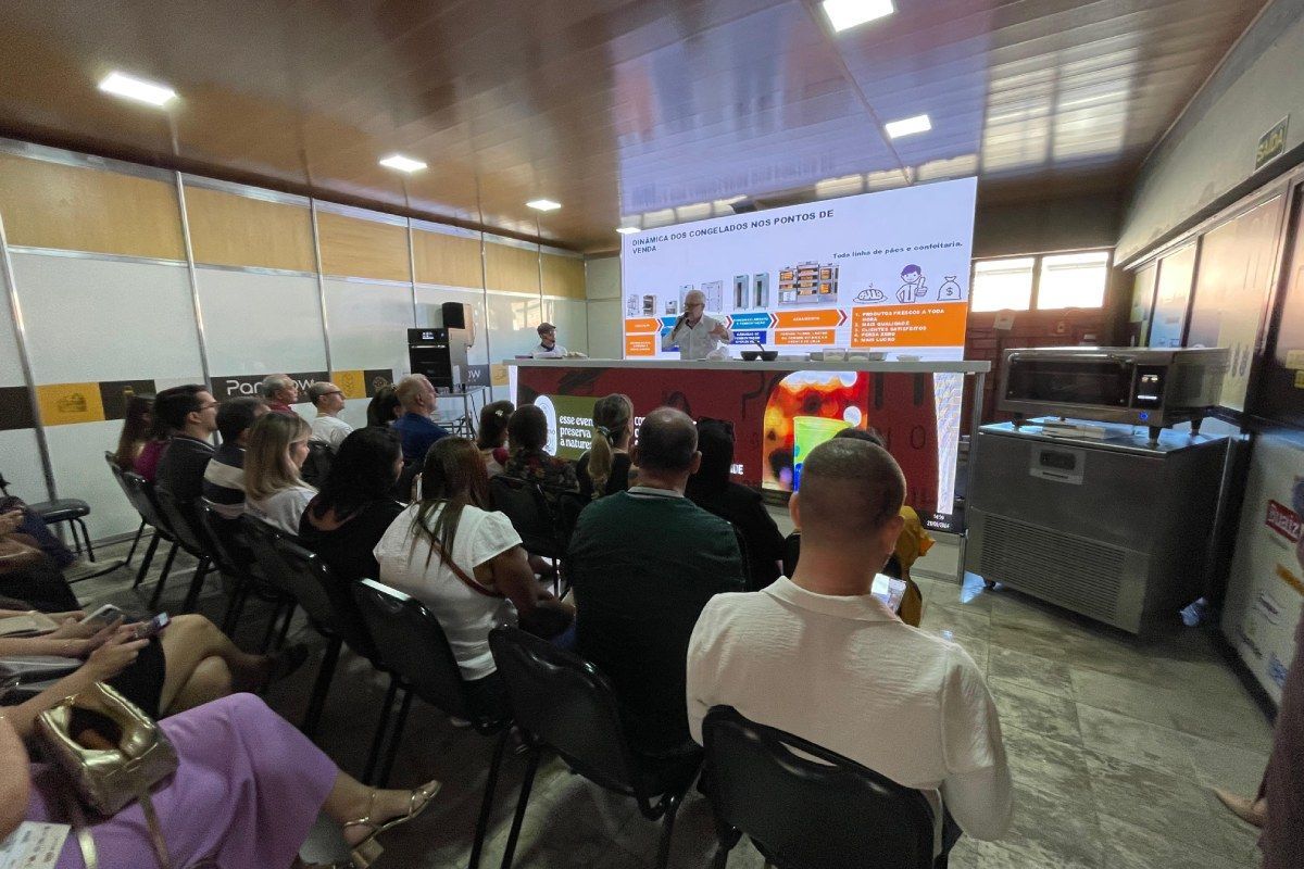 Um grupo de pessoas está sentado em cadeiras em frente a uma tela grande.