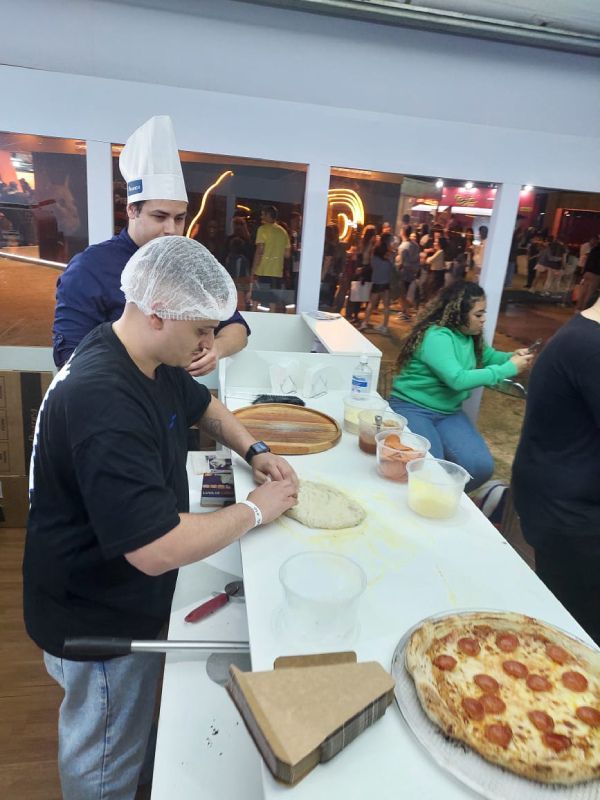 Um homem com chapéu de chef está preparando uma pizza de calabresa
