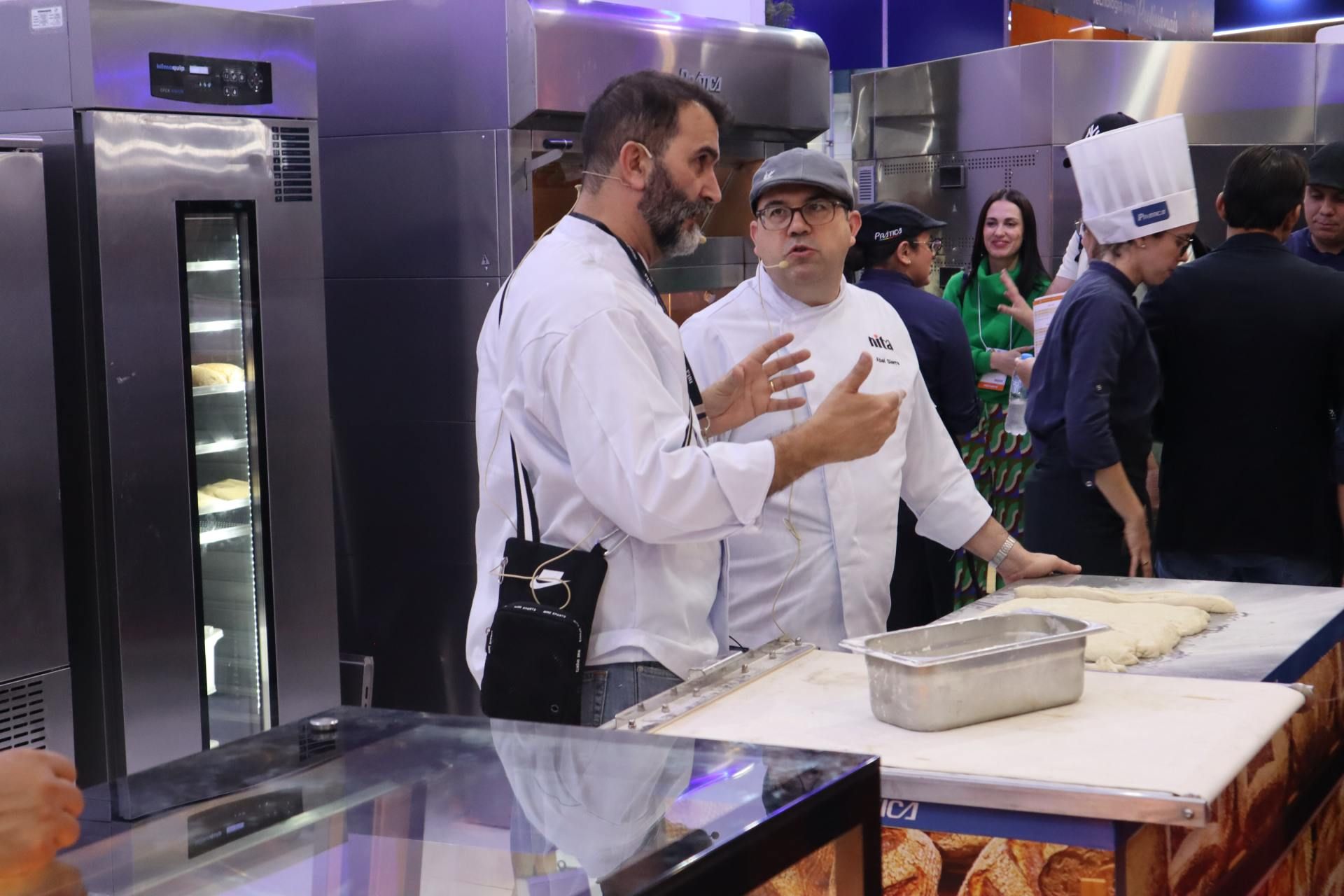 Dois homens estão em pé na cozinha conversando um com o outro.