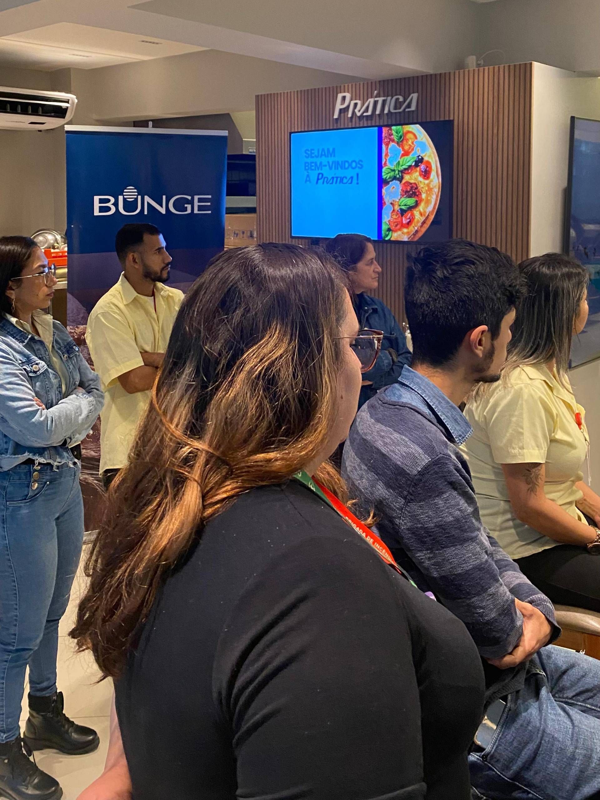 Um grupo de pessoas está sentado em uma sala assistindo a uma apresentação.