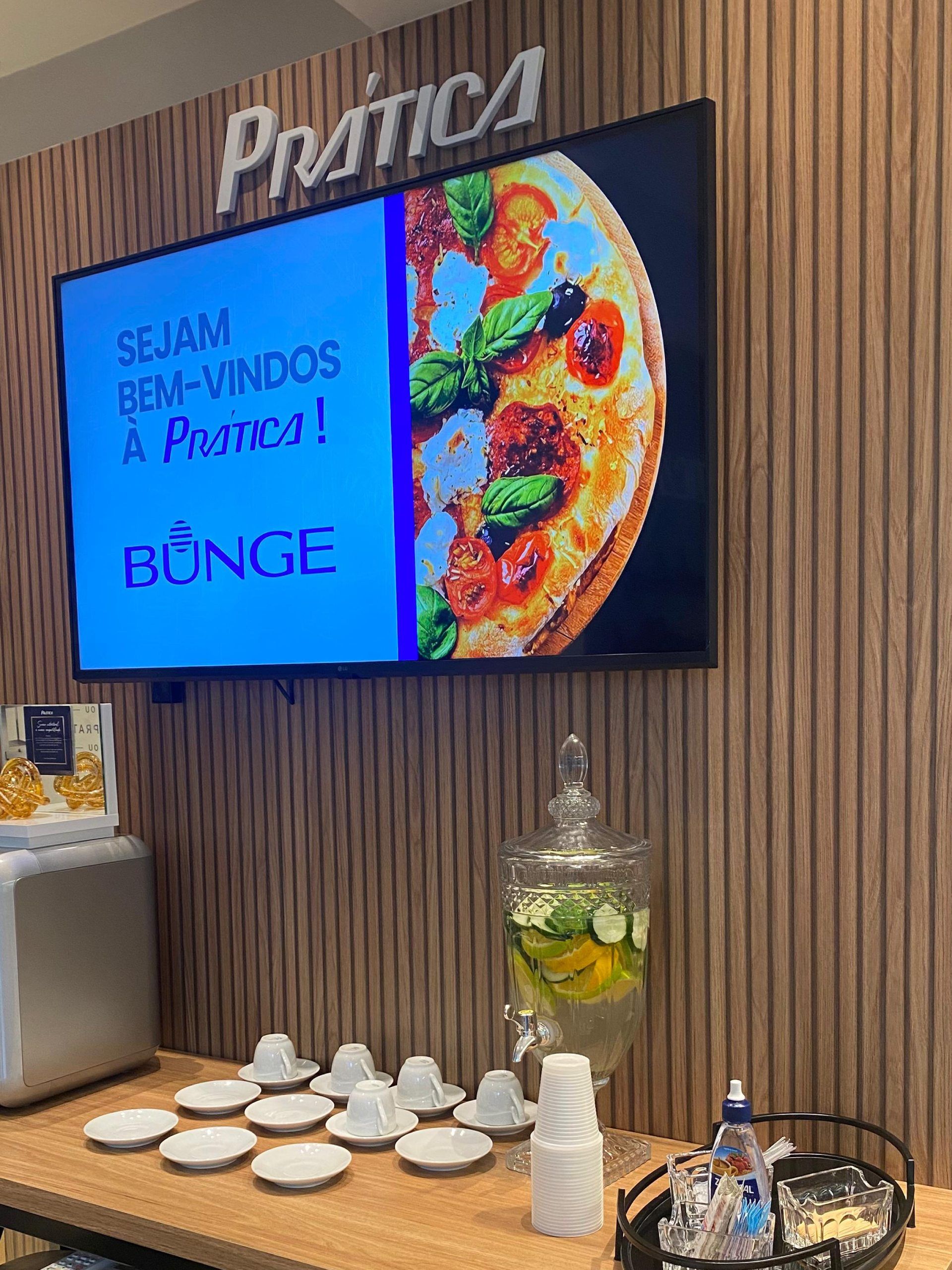 Uma grande TV de tela plana está pendurada em uma parede de madeira acima de uma mesa.