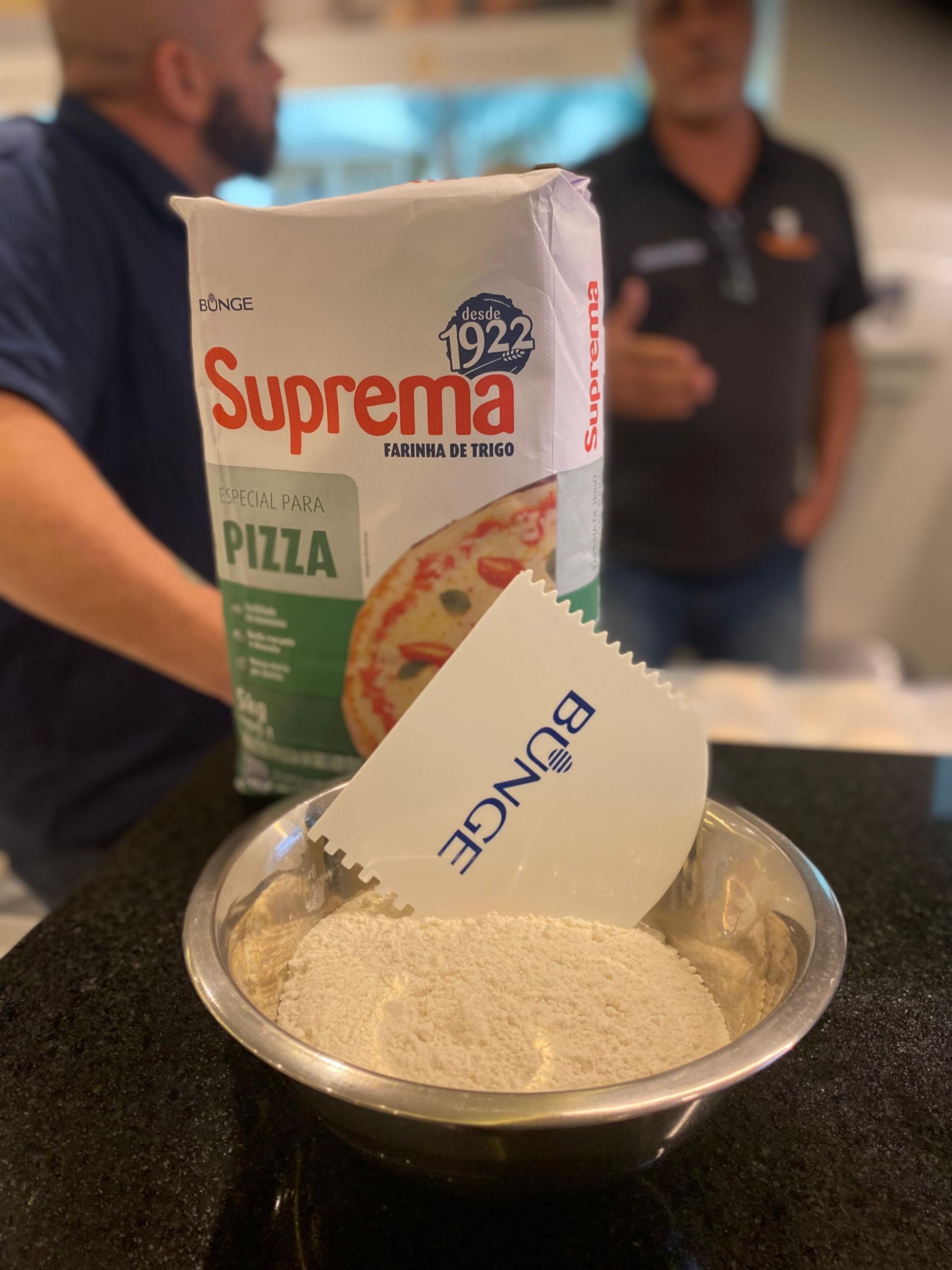 Um saco de farinha de pizza suprema ao lado de uma tigela de farinha