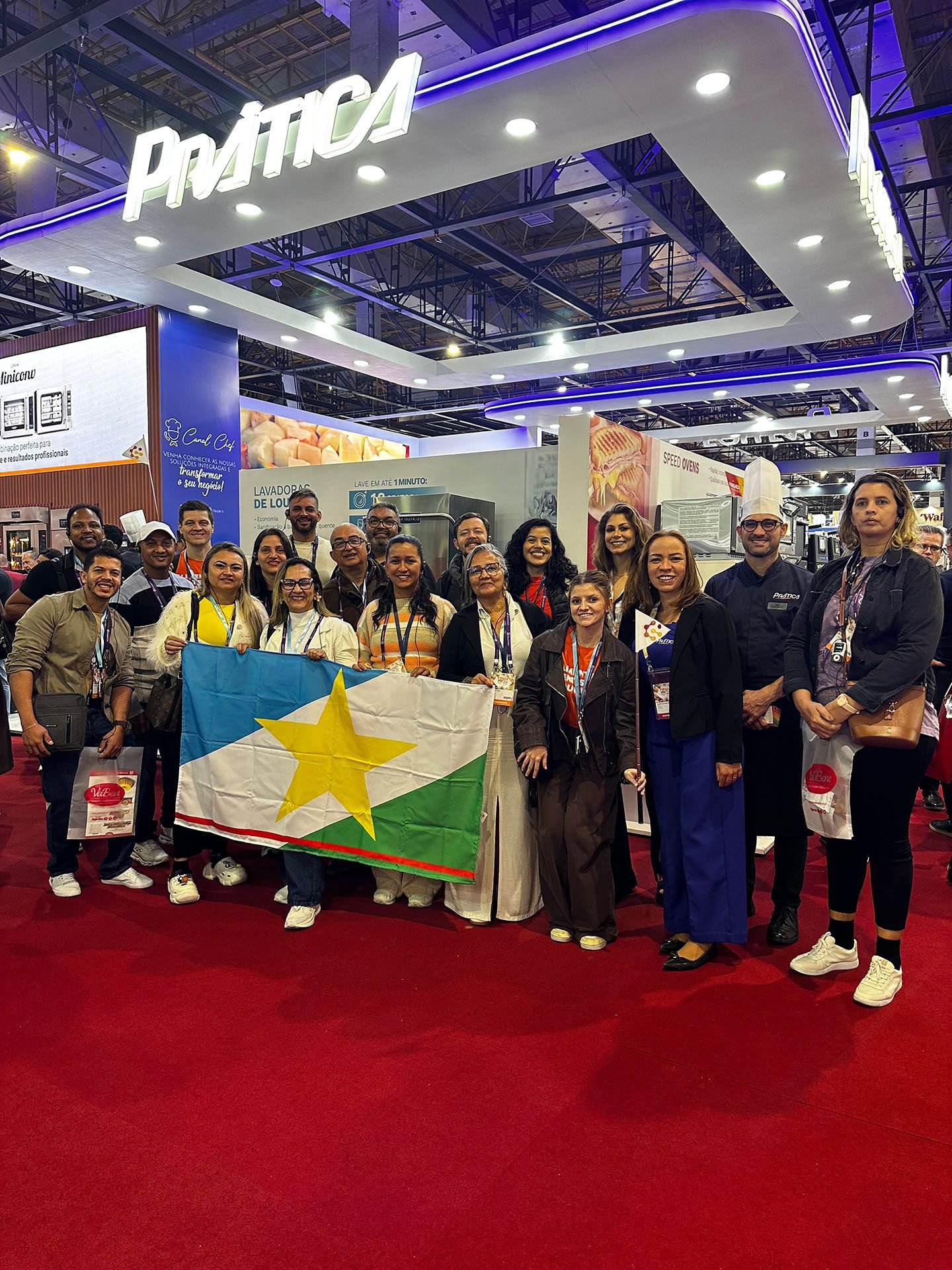 Um grupo de pessoas em pé sobre um tapete vermelho segurando uma bandeira.