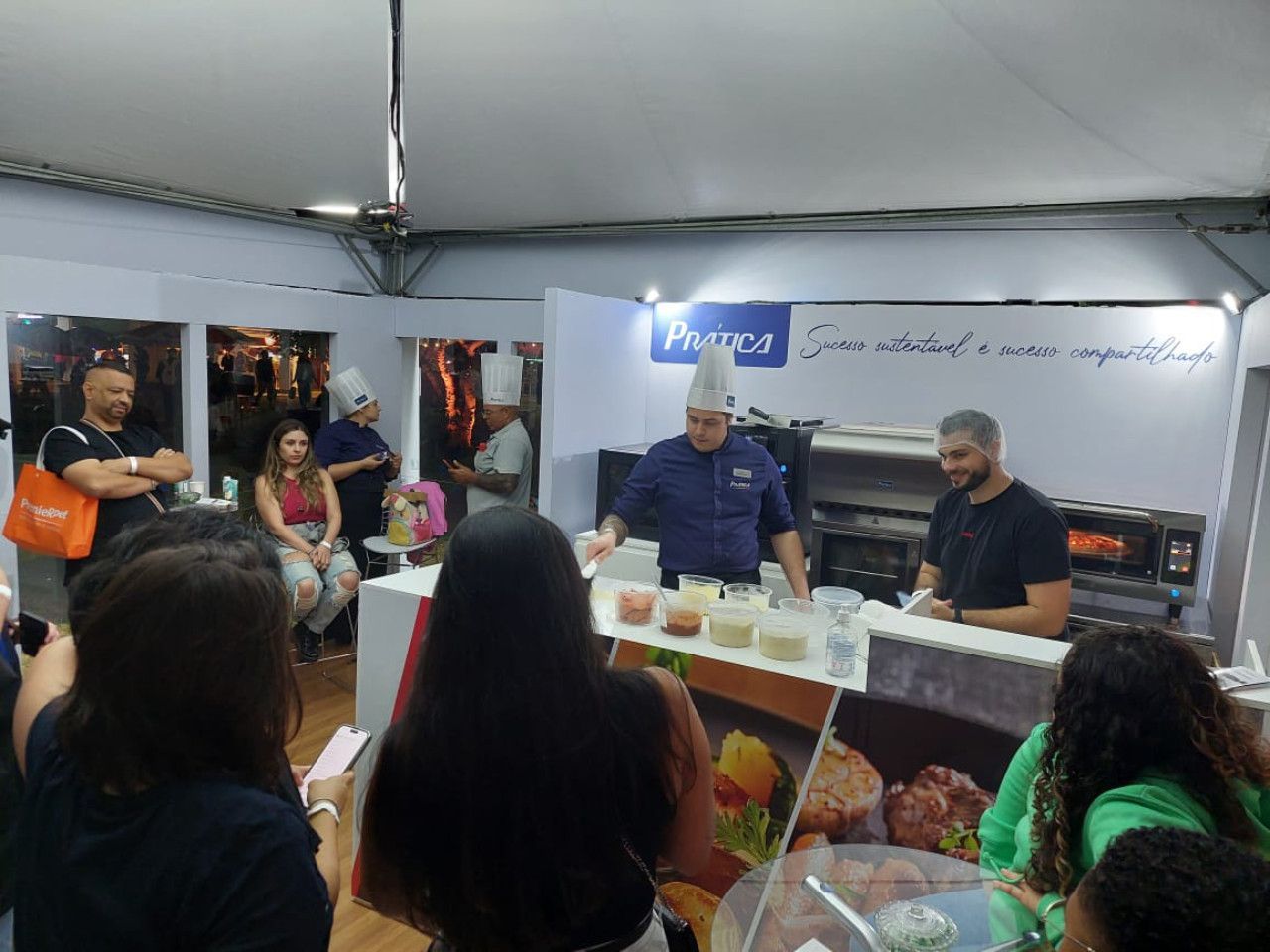 Um grupo de pessoas está observando um chef preparando comida em uma cozinha.