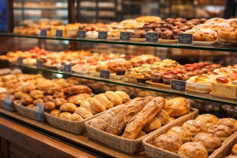 Vitrine de padaria repleta de pães e doces frescos variados.