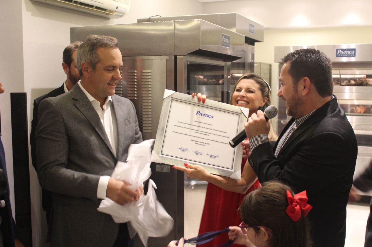 Um homem de terno está dando um certificado para uma mulher de vestido vermelho