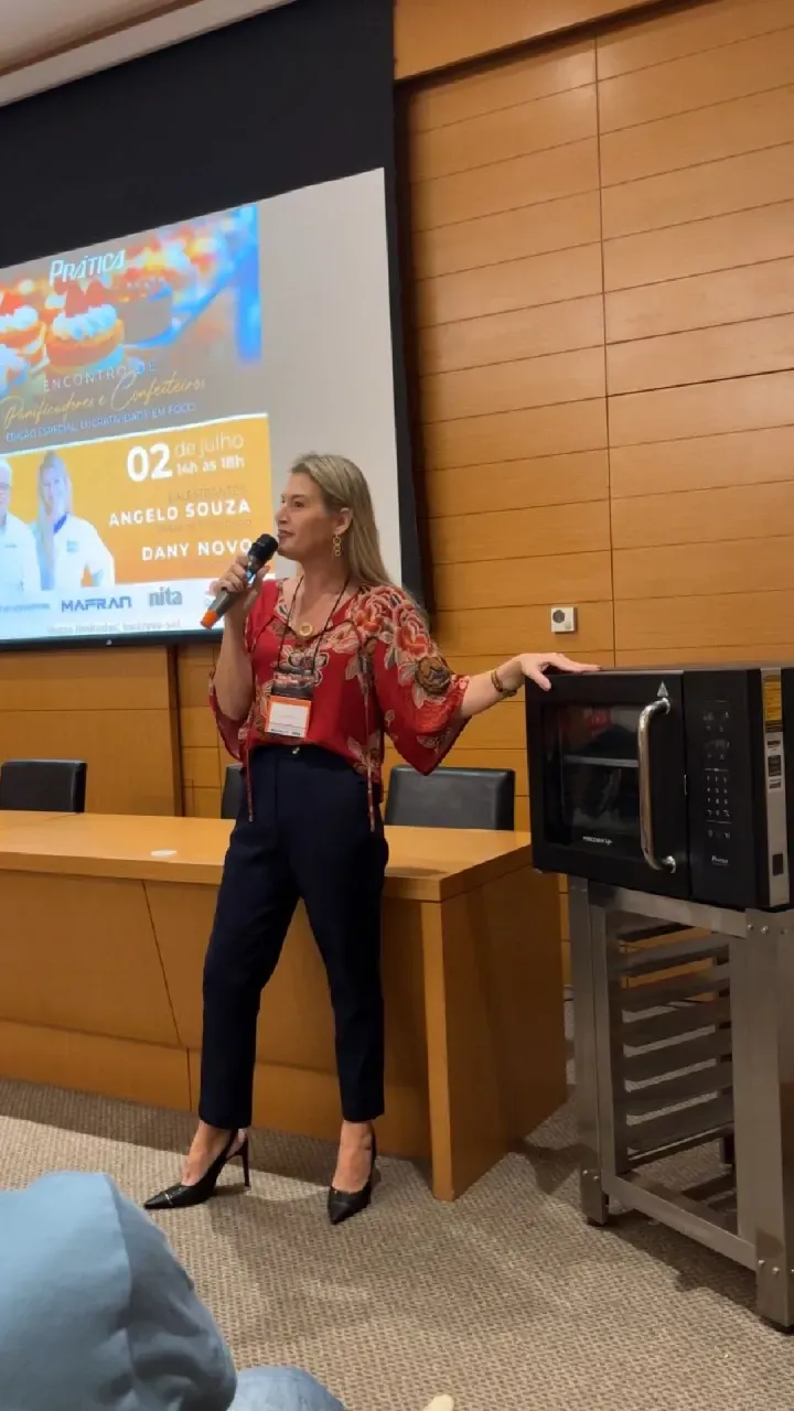 Uma mulher está em frente a um micro-ondas e fazendo uma apresentação.