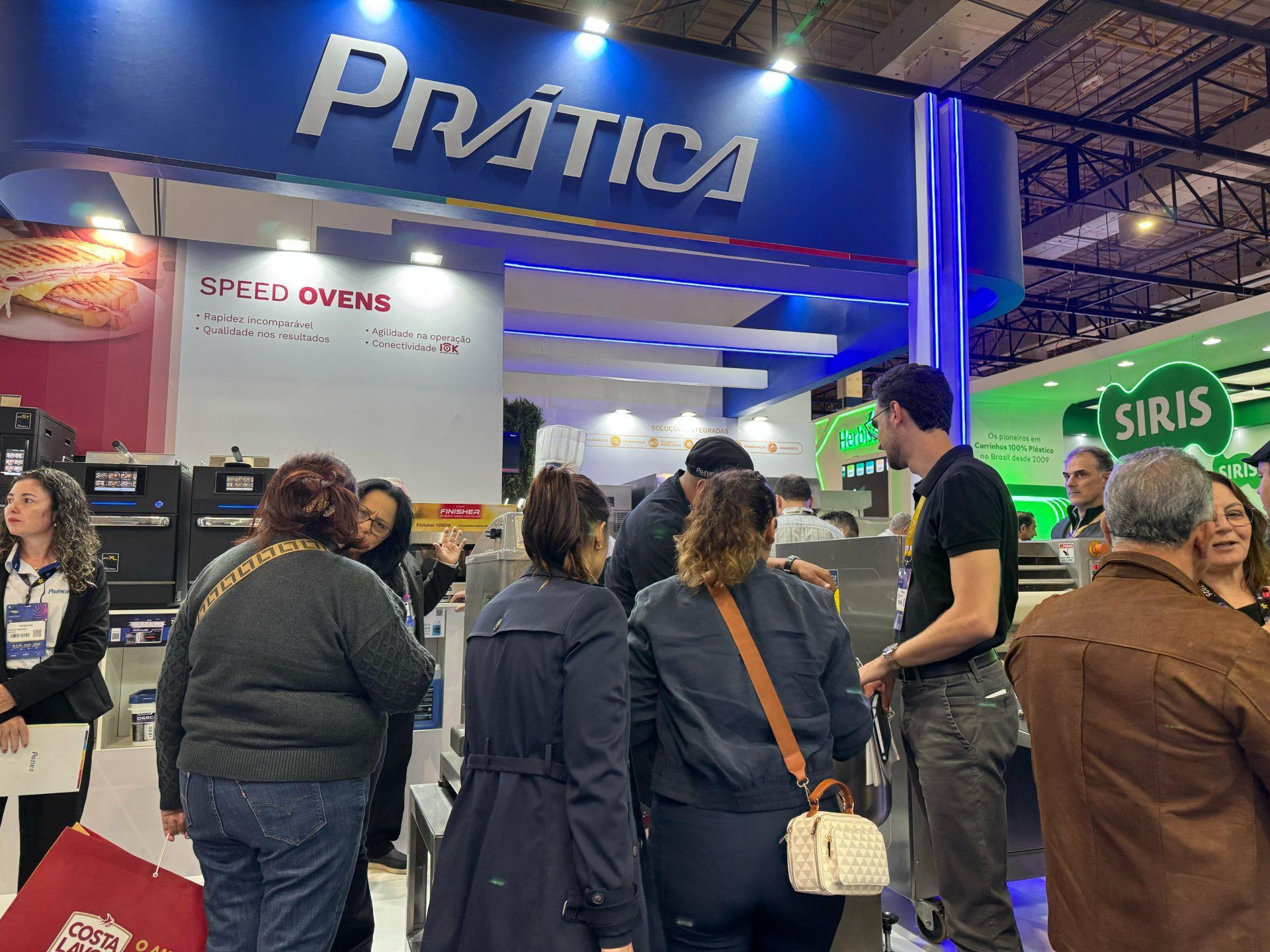 Um grupo de pessoas está em frente a um estande em uma convenção.