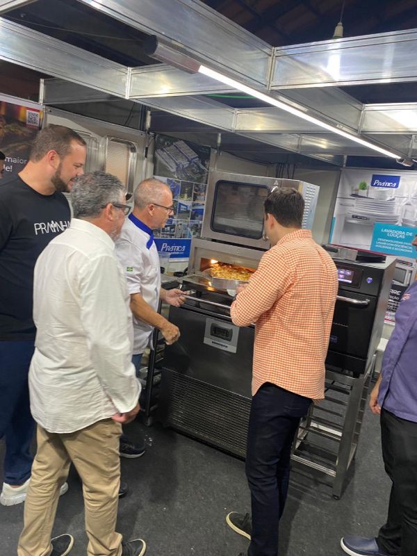 Um grupo de homens está em volta de uma máquina em uma cozinha.