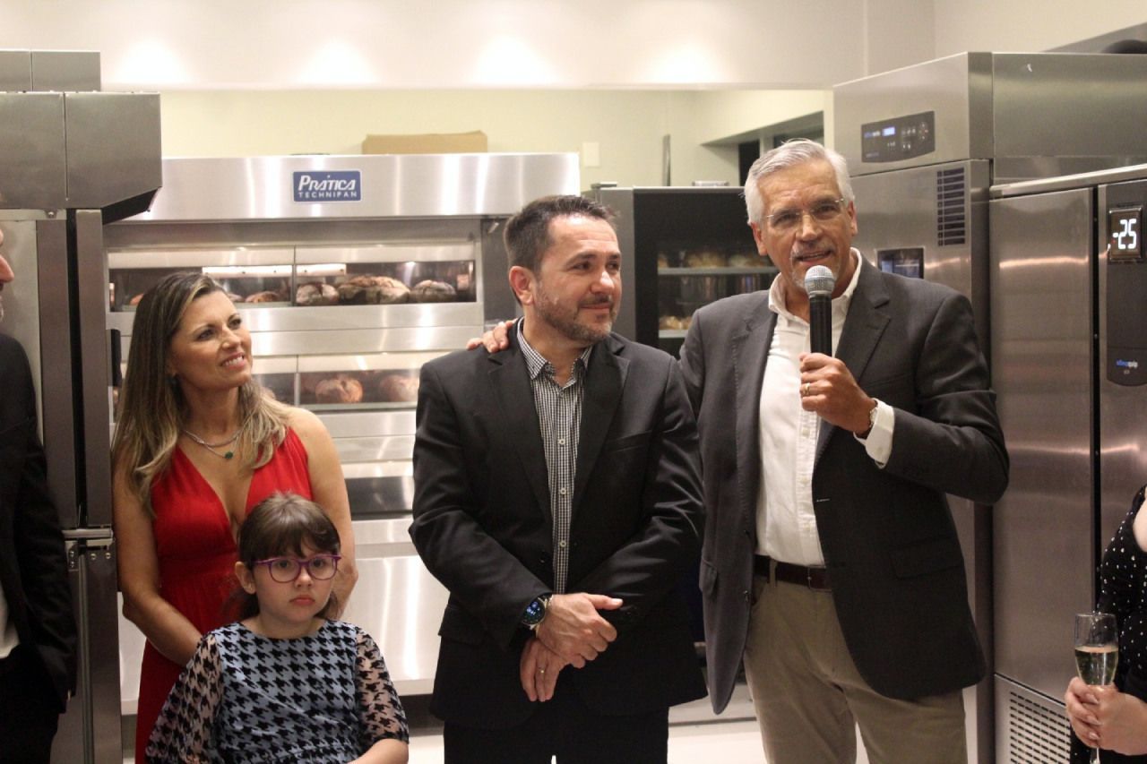 Um grupo de pessoas em uma cozinha com um homem segurando um microfone