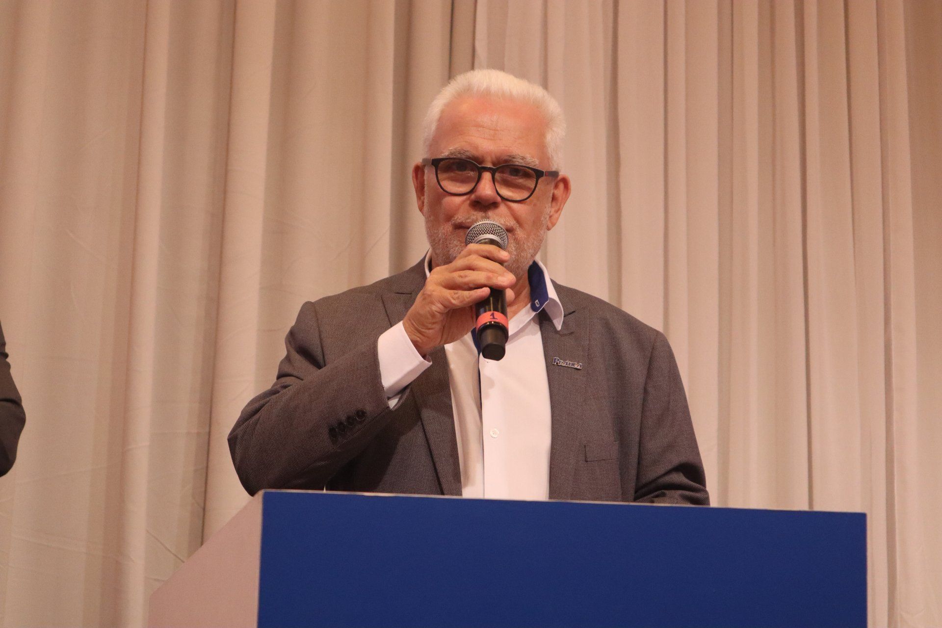 Um homem está de pé em um pódio segurando um microfone.