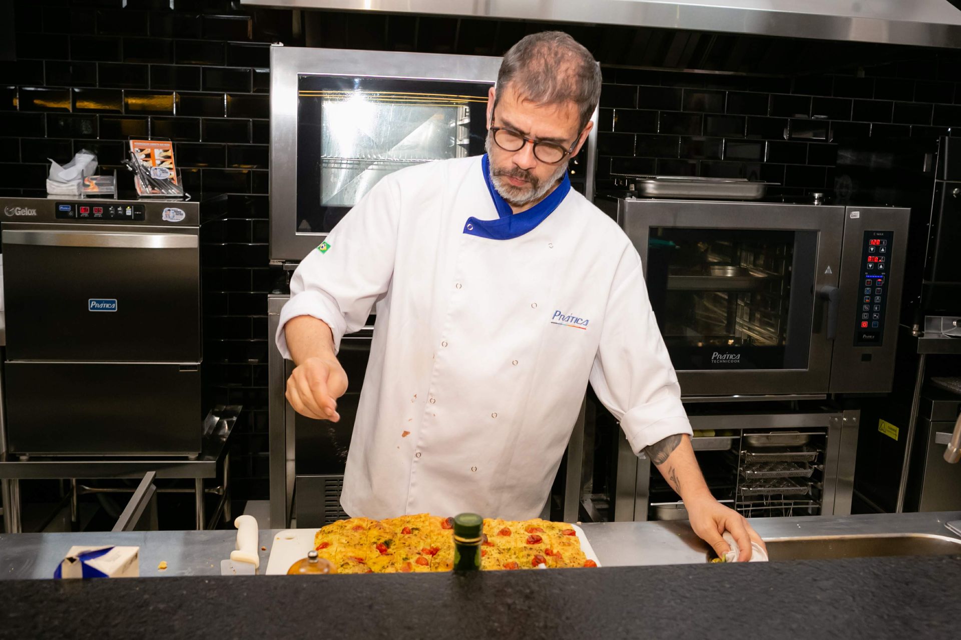 Um homem com uniforme de chef está preparando comida em uma cozinha.