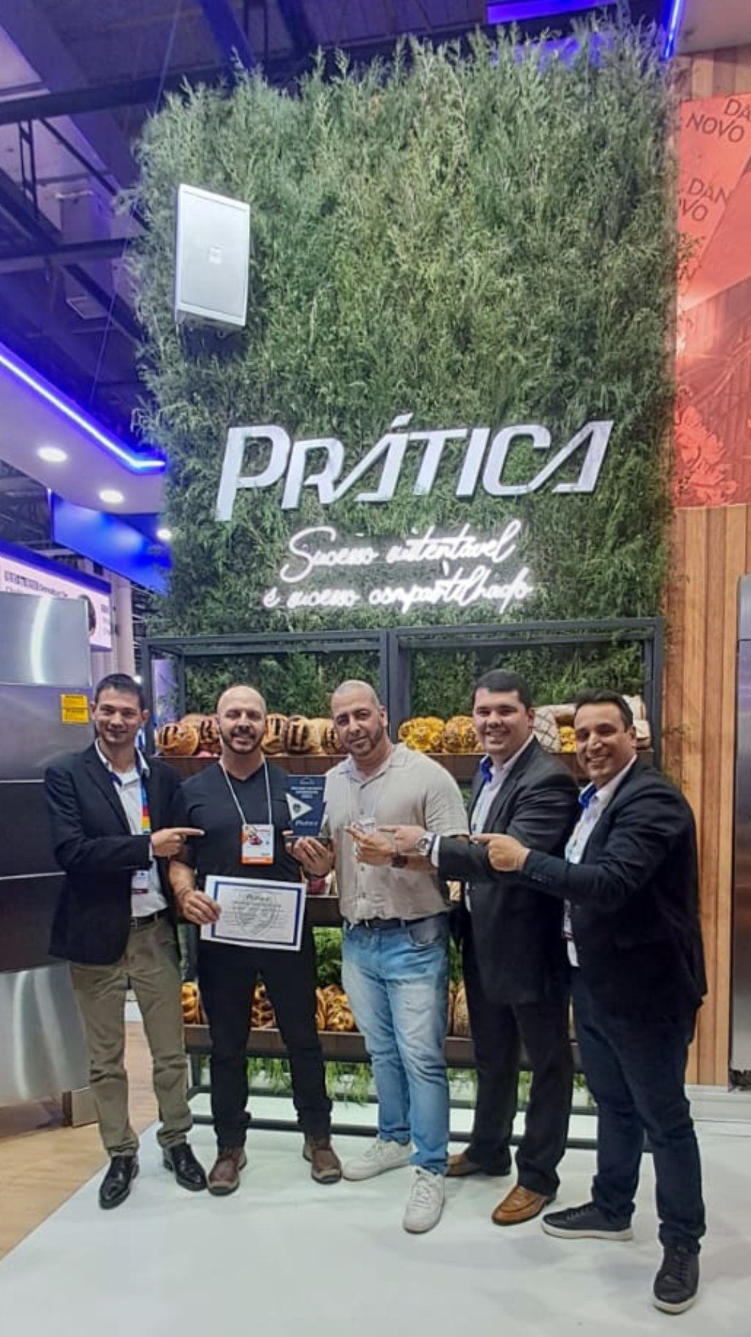 Um grupo de homens posa para uma foto em frente a uma parede verde.