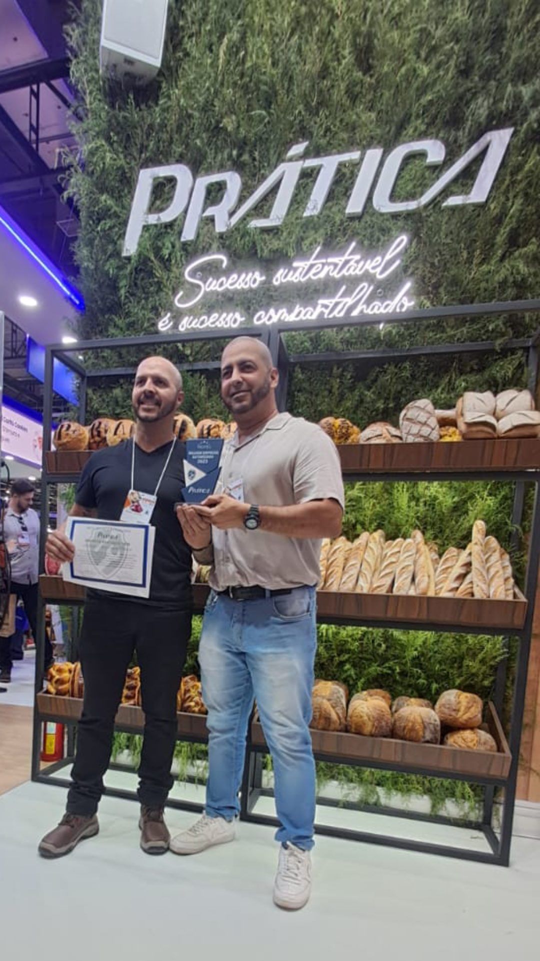 Dois homens estão parados um ao lado do outro em frente a uma vitrine de pães.