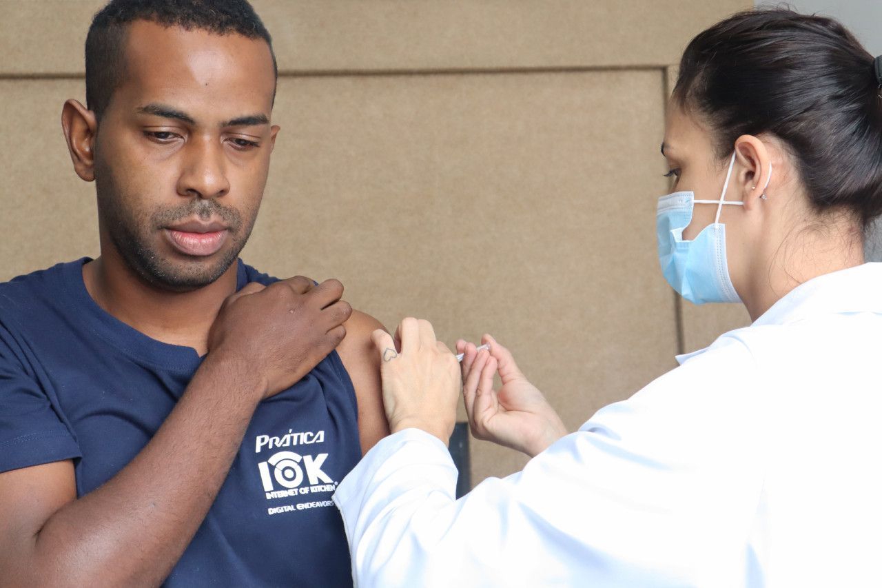 Um homem está sendo vacinado por uma médica