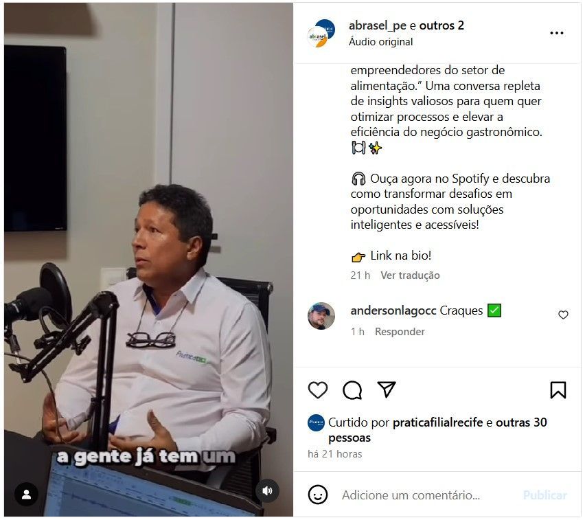 Um homem está sentado em frente a um microfone e falando nele.