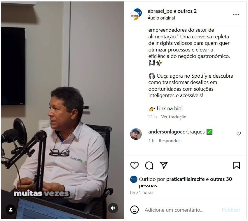 Um homem está sentado em frente a um microfone em uma sala.