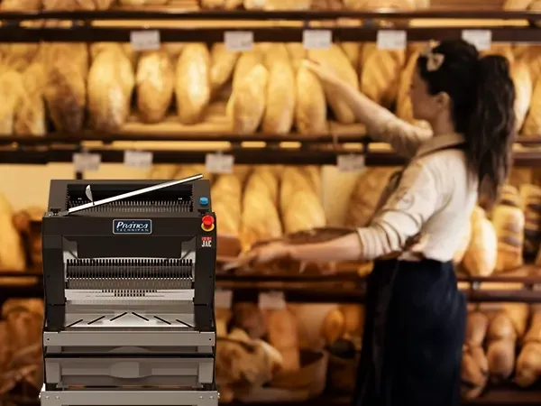 Uma mulher está parada em frente a uma máquina em uma padaria.