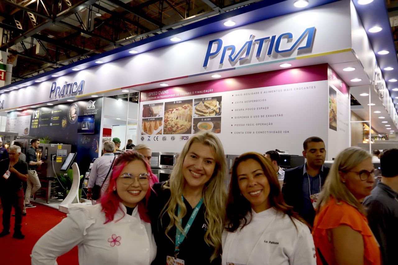Três mulheres estão posando para uma foto em frente a uma placa de prática.