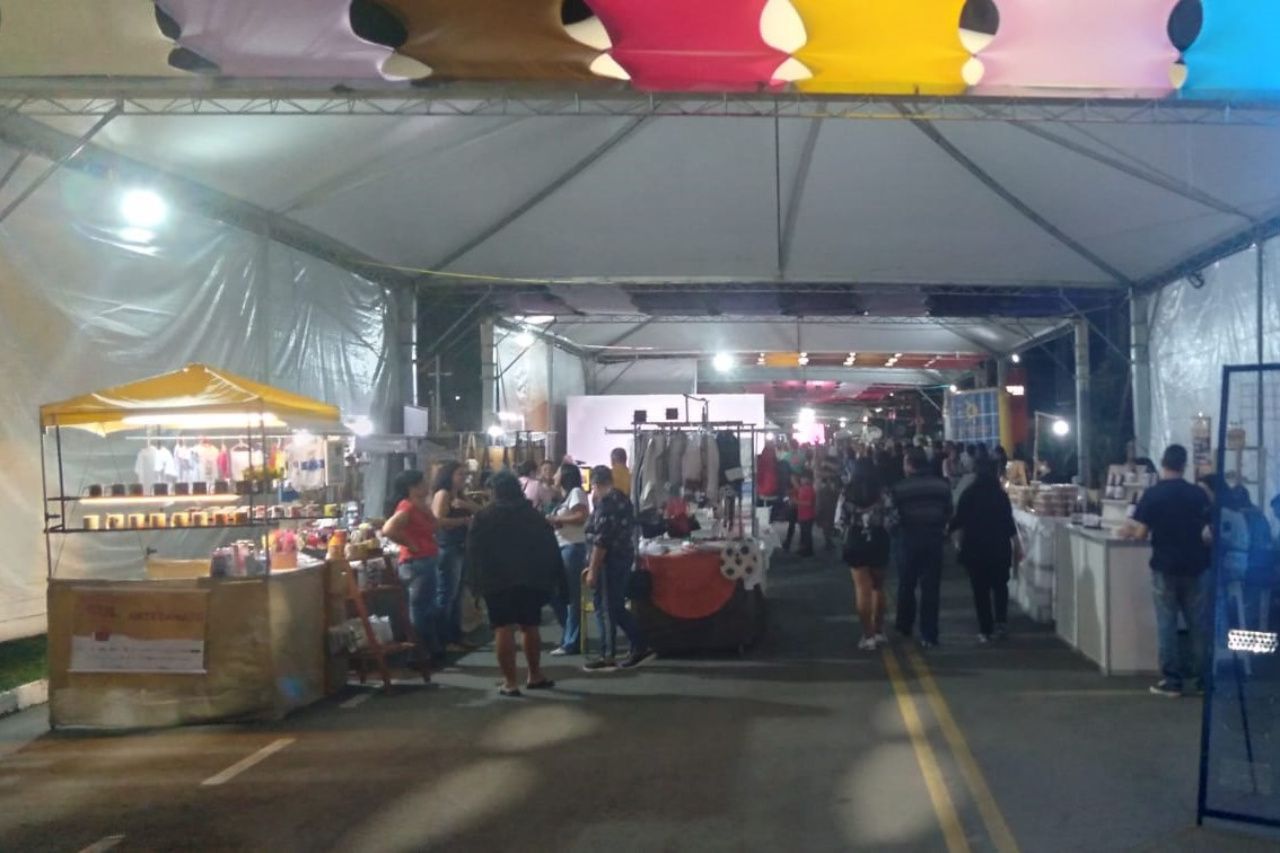 Um grupo de pessoas está em pé sob uma tenda em um mercado.