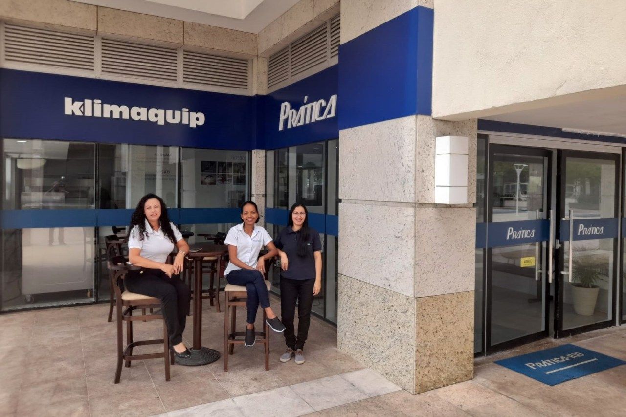 Três mulheres estão sentadas em bancos em frente a um prédio.