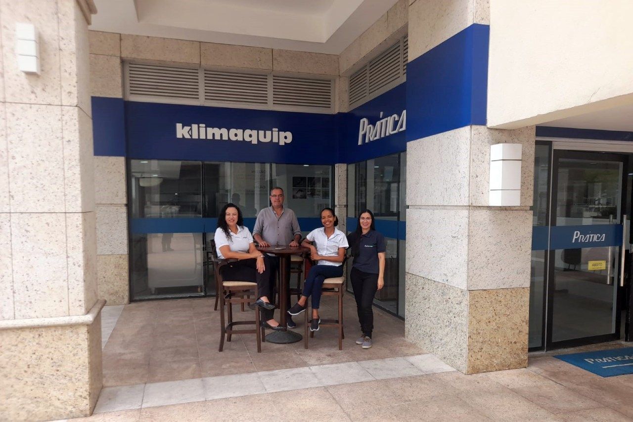 Um grupo de pessoas em pé do lado de fora de um prédio que diz klimaquip