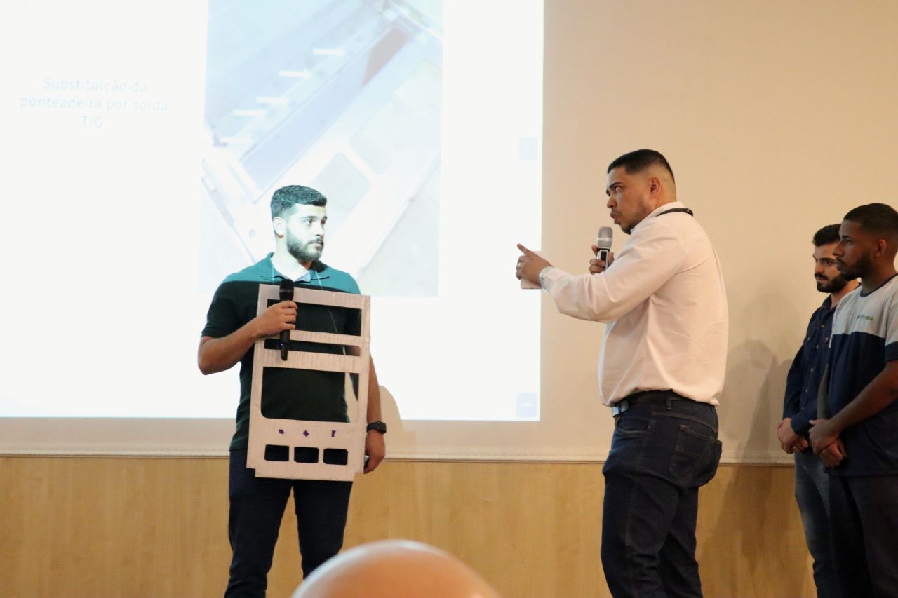 Um grupo de homens está em frente a uma tela de projeção.