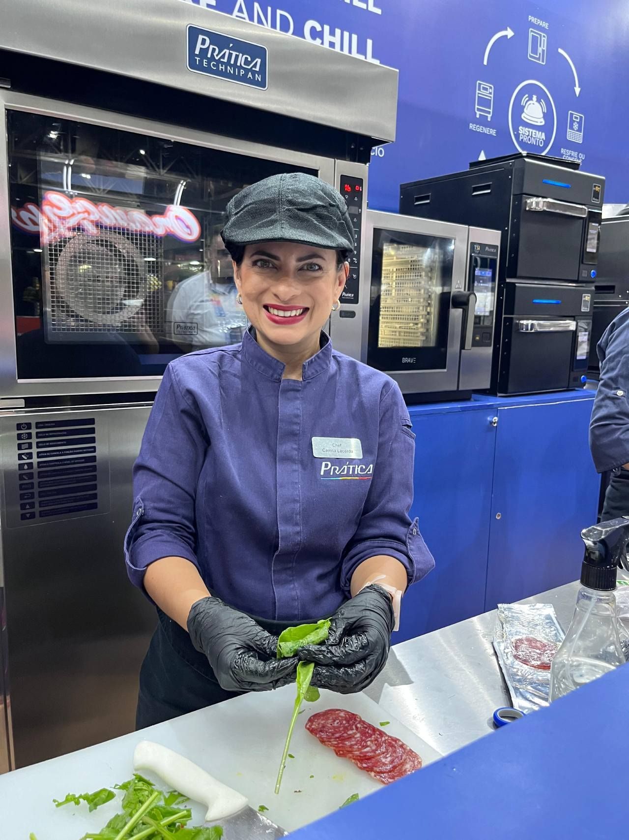 Uma mulher está parada em um balcão cortando vegetais e sorrindo.