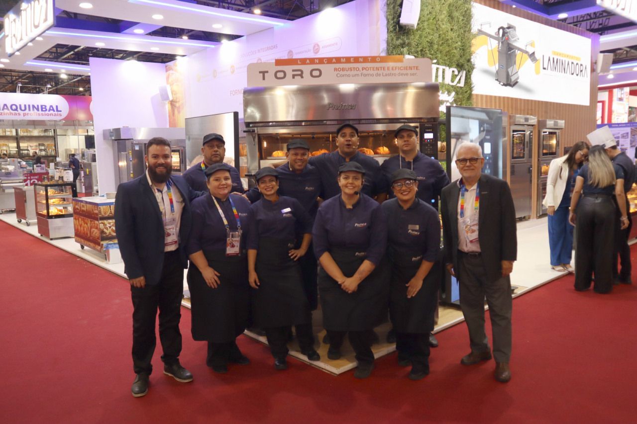 Um grupo de pessoas está posando para uma foto em frente a um forno.