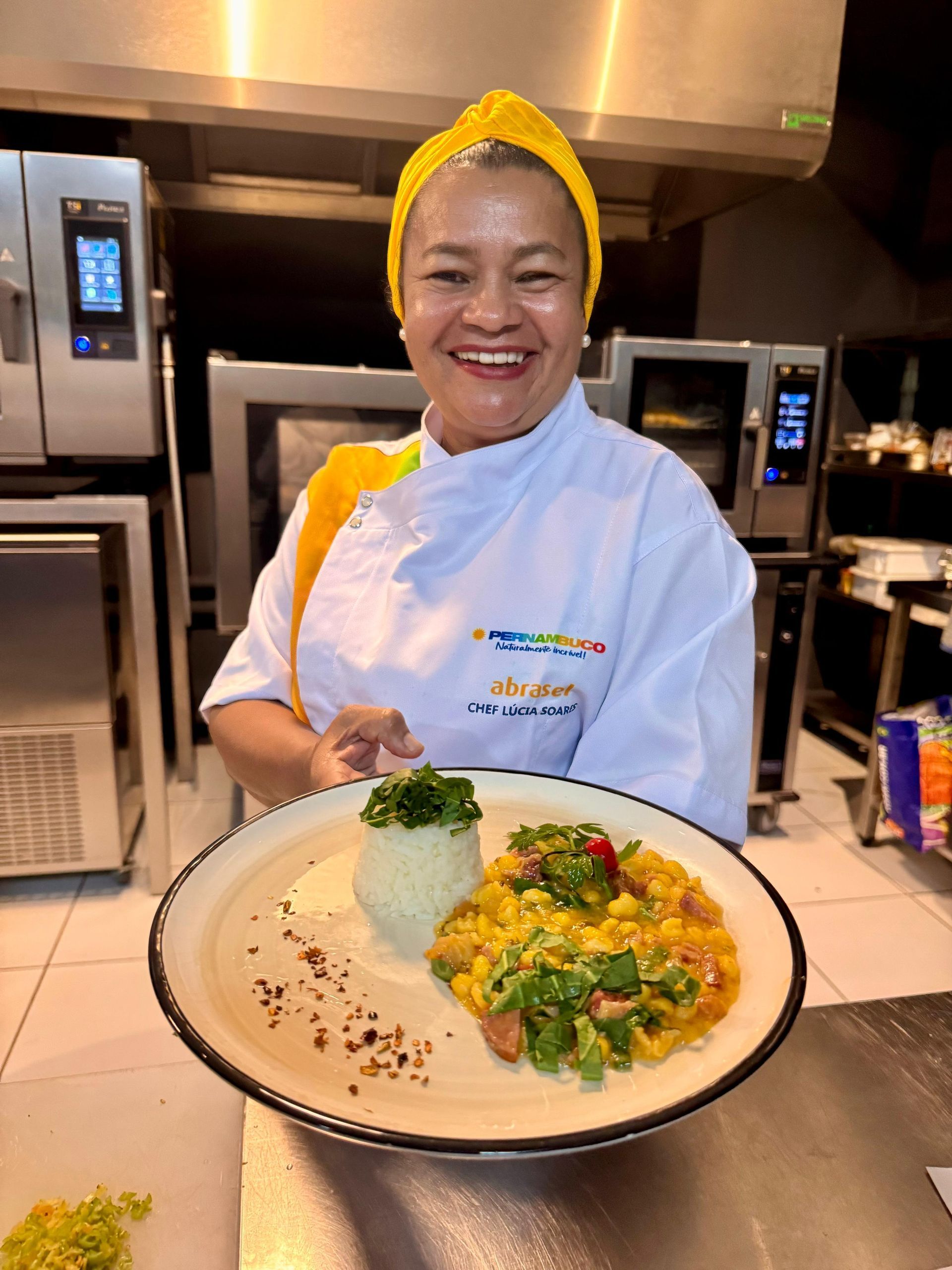 Uma mulher com uniforme de chef segura um prato de comida