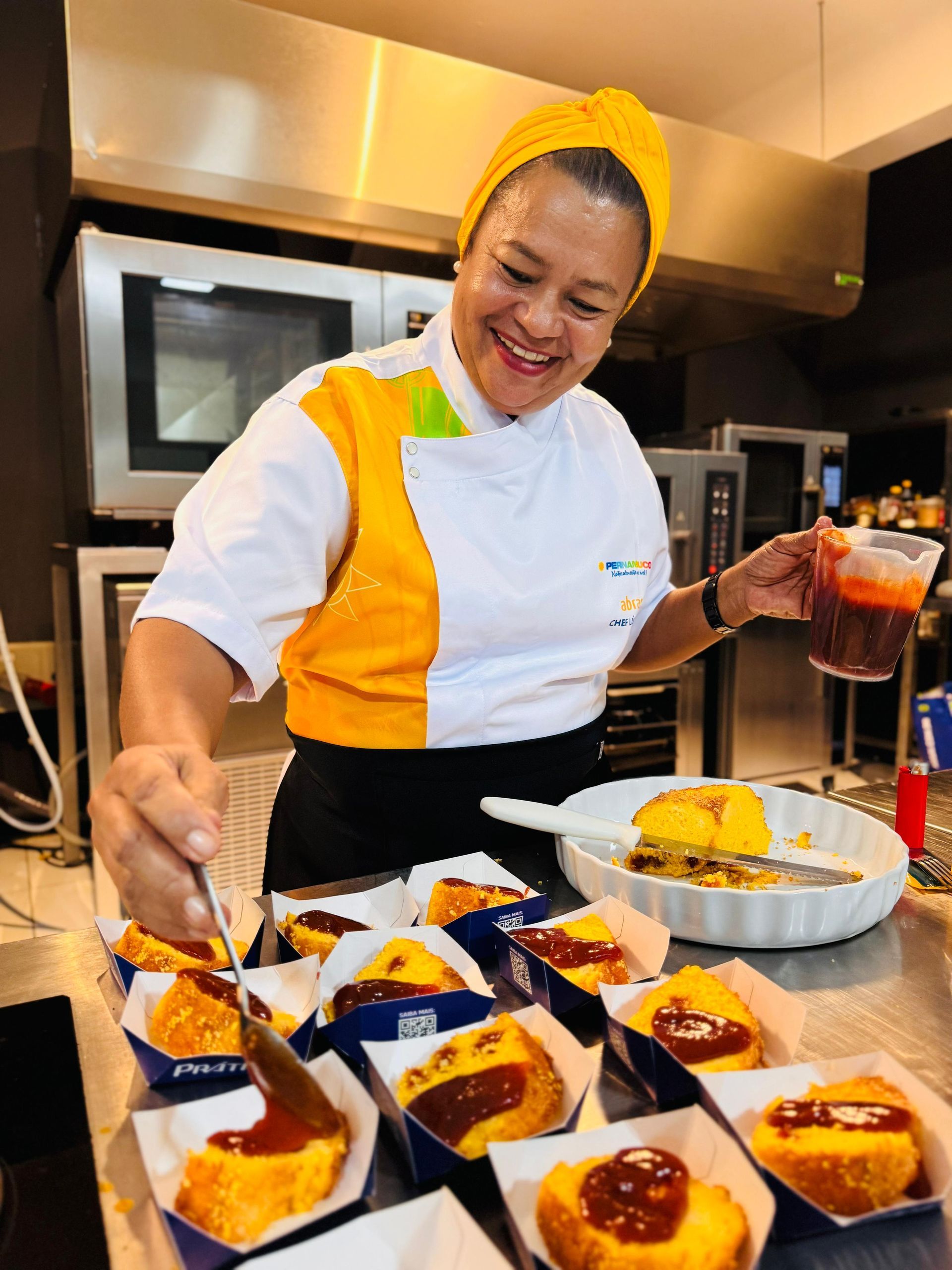 Uma mulher com uniforme de chef está preparando comida em uma cozinha.