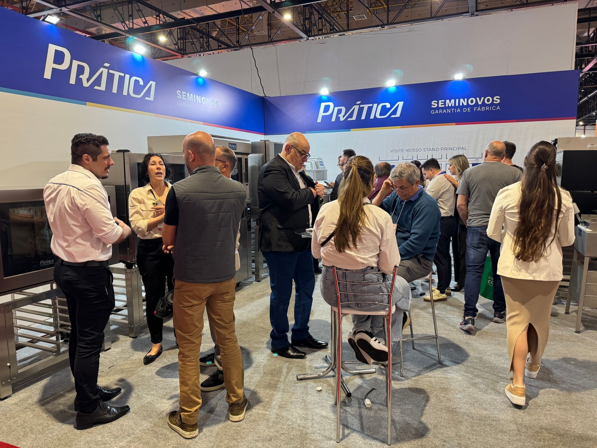 Um grupo de pessoas está em volta de um estande em uma convenção.