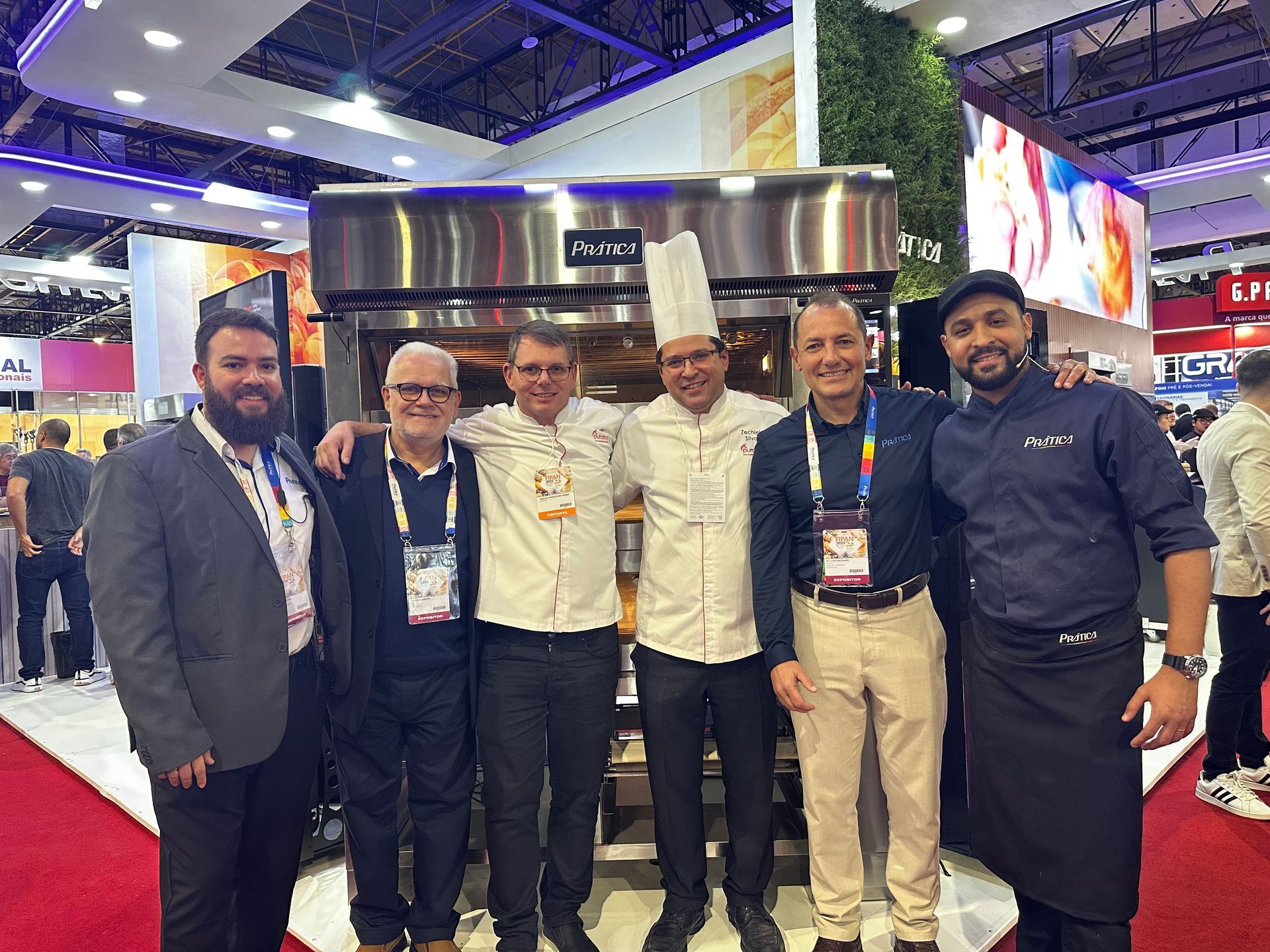 Um grupo de homens está posando para uma foto em frente a um forno.