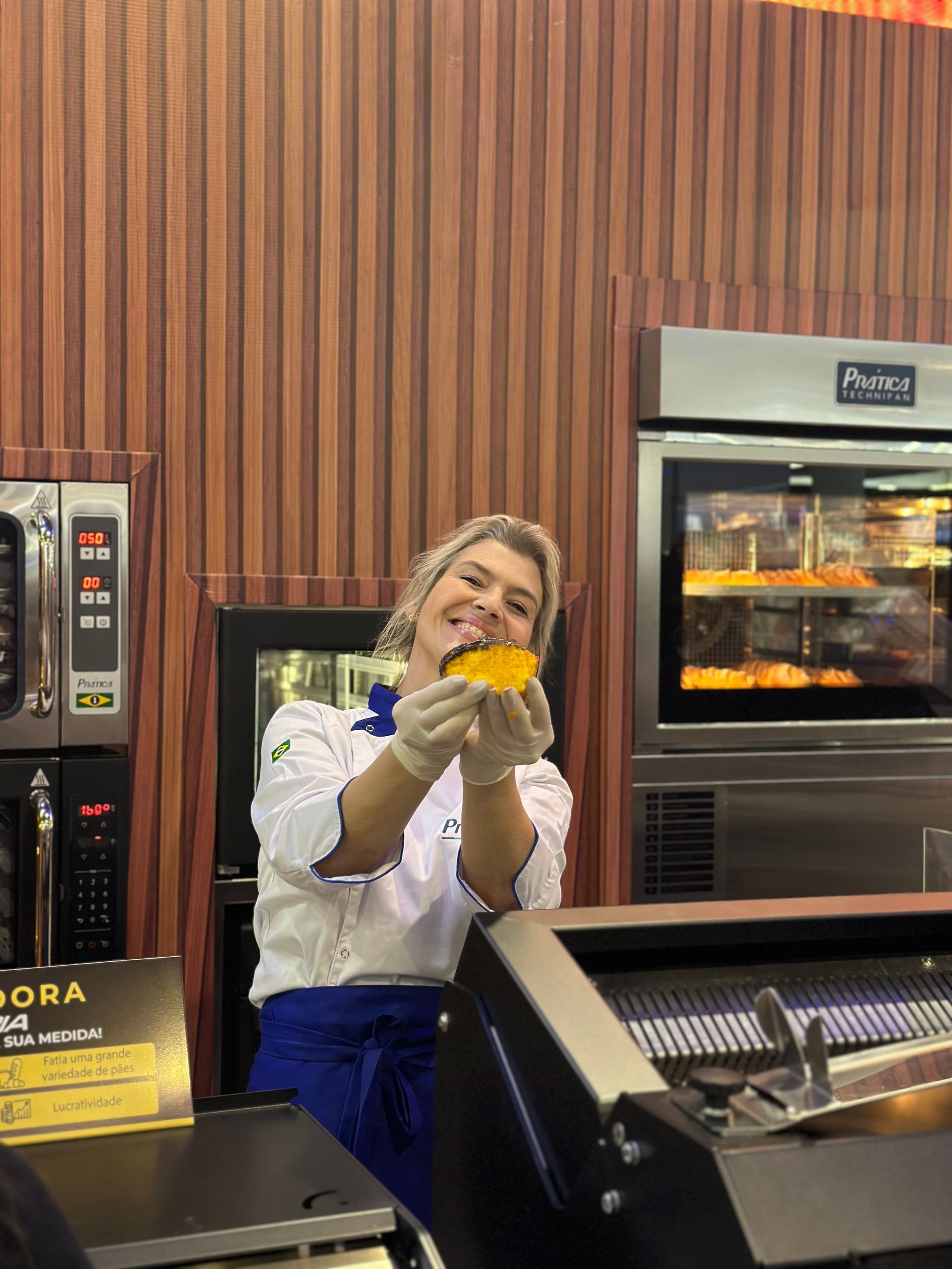 Uma mulher segura um pedaço de comida nas mãos em uma cozinha.